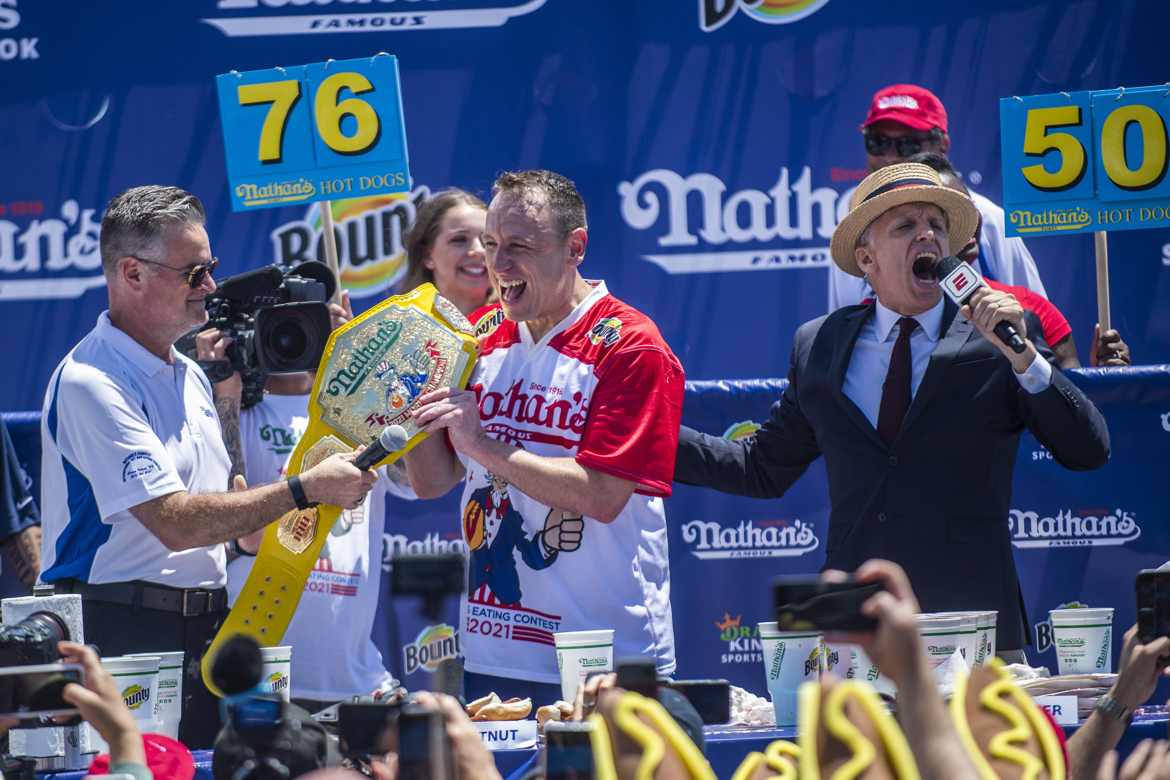 Joey Chestnut, center, reacts after winning the Nathan's Famous Fourth of July International Hot Dog-Eating Contest in Coney Island's Maimonides Park on Sunday, July 4, 2021, in New York. (AP Photo/Brittainy Newman)