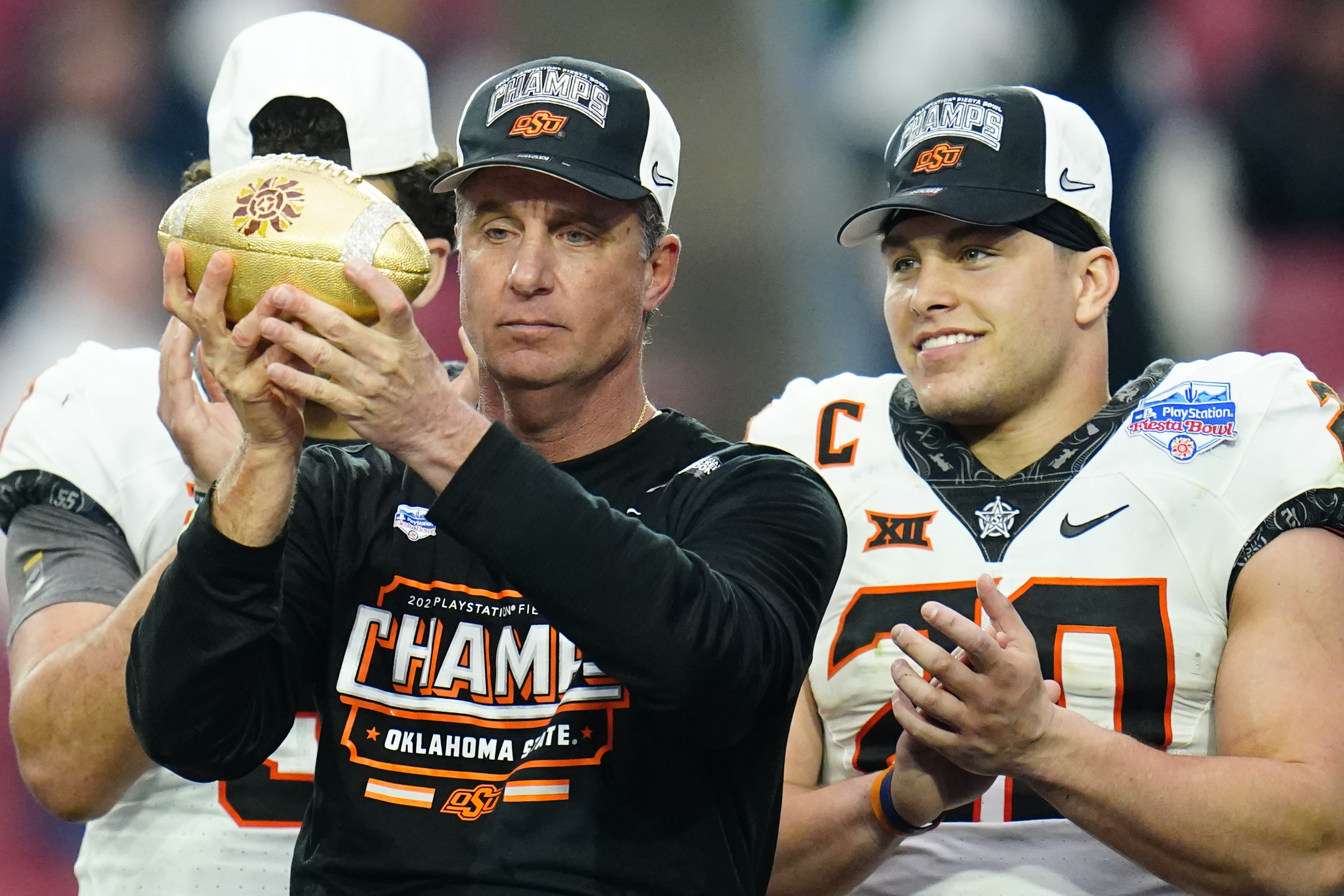 Oklahoma State head coach Mike Gundy hoists the Fiesta Bowl Champions Trophy after the Fiesta Bowl NCAA college football game against Notre Dame, Saturday, Jan. 1, 2022, in Glendale, Ariz. Oklahoma State won 37-35. (AP Photo/Ross D. Franklin)