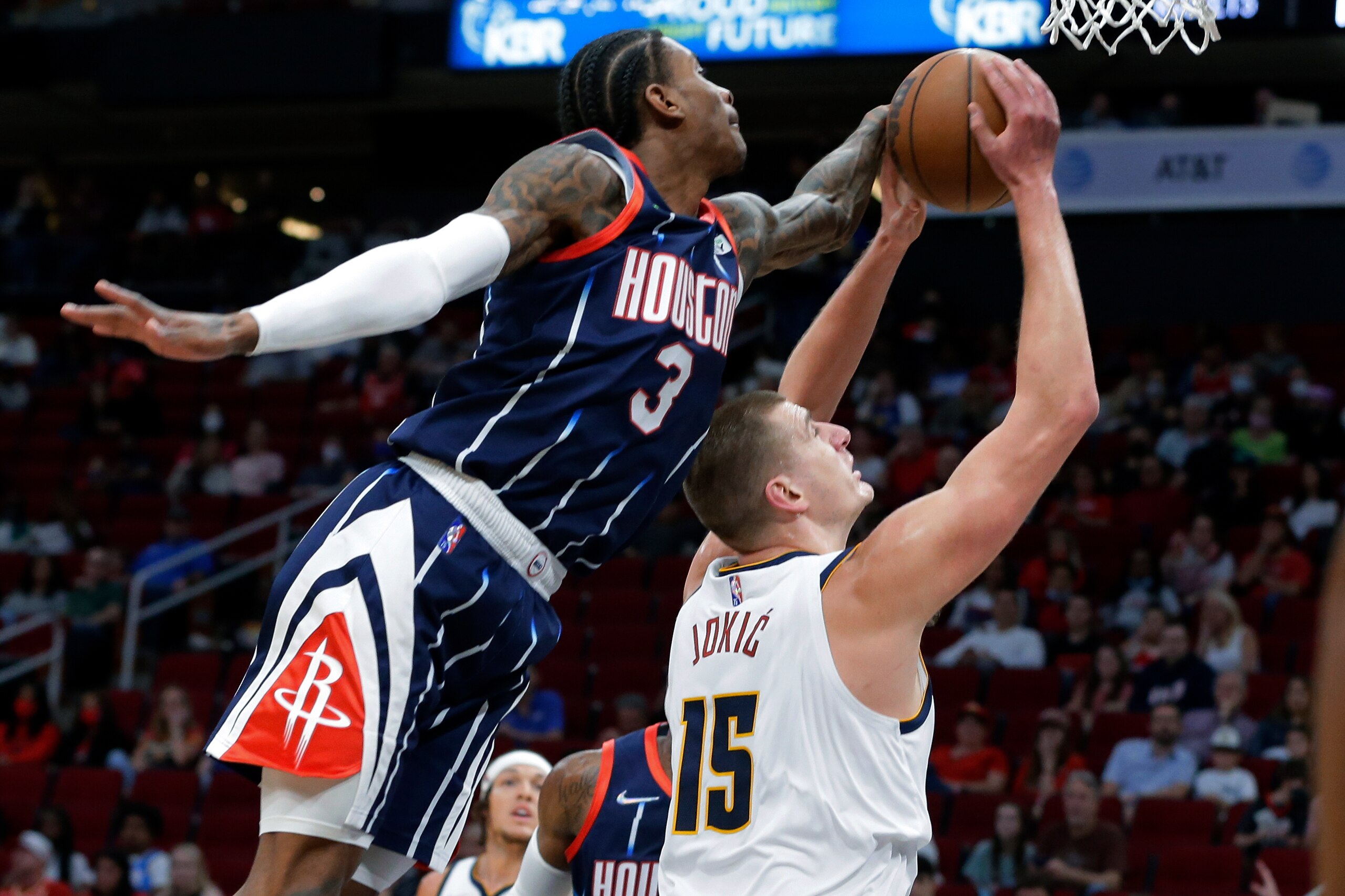 Houston Rockets guard Kevin Porter Jr. (3) reaches over to block the shot attempt by Denver Nuggets center Nikola Jokic (15) during the first half of an NBA basketball game Saturday, Jan. 1, 2022, in Houston. (AP Photo/Michael Wyke)