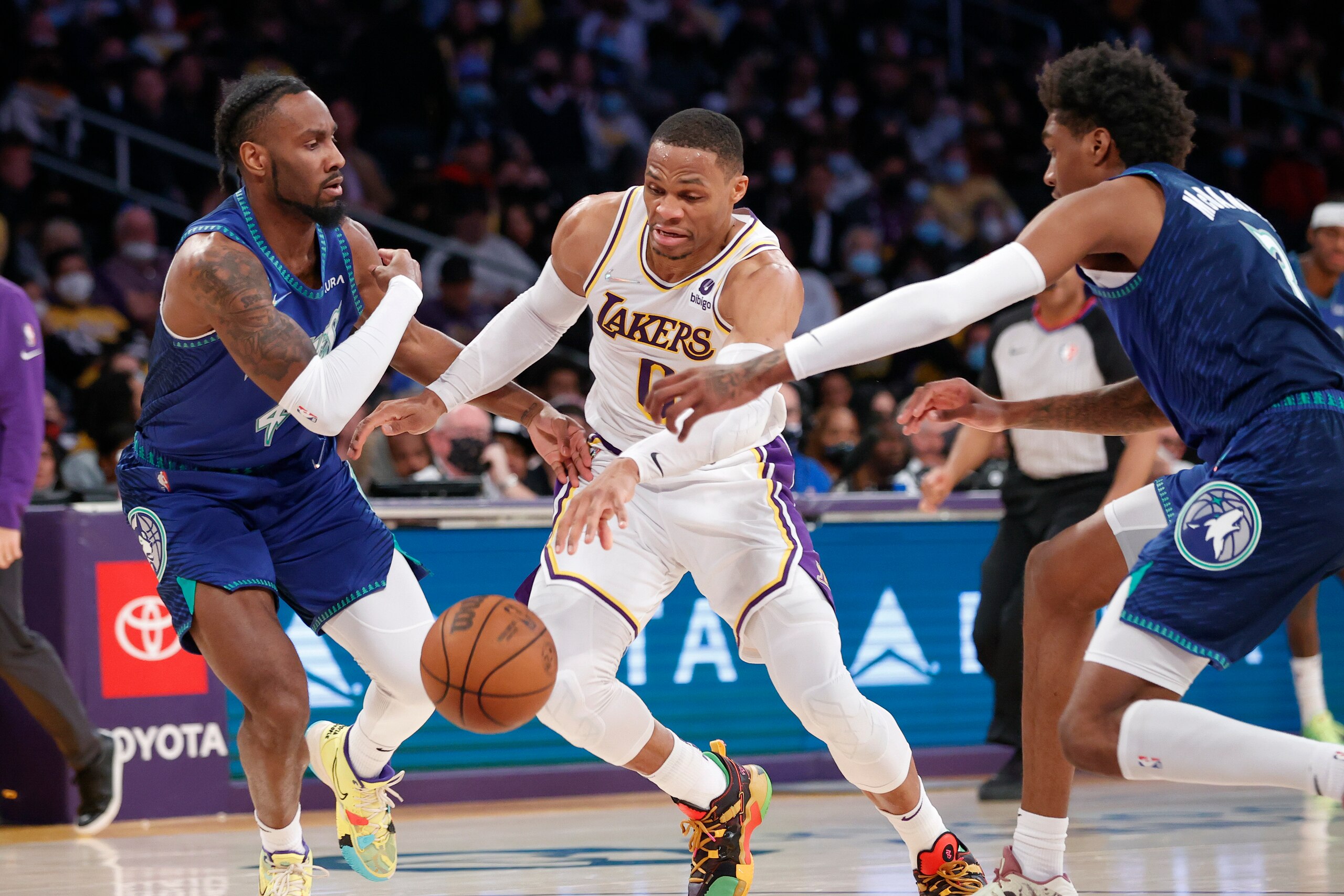 Los Angeles Lakers guard Russell Westbrook, center, drives between Minnesota Timberwolves guard Jaylen Nowell, left, and forward Jaden McDaniels during the first half of an NBA basketball game in Los Angeles, Sunday, Jan. 2, 2022. (AP Photo/Ringo H.W. Chiu)