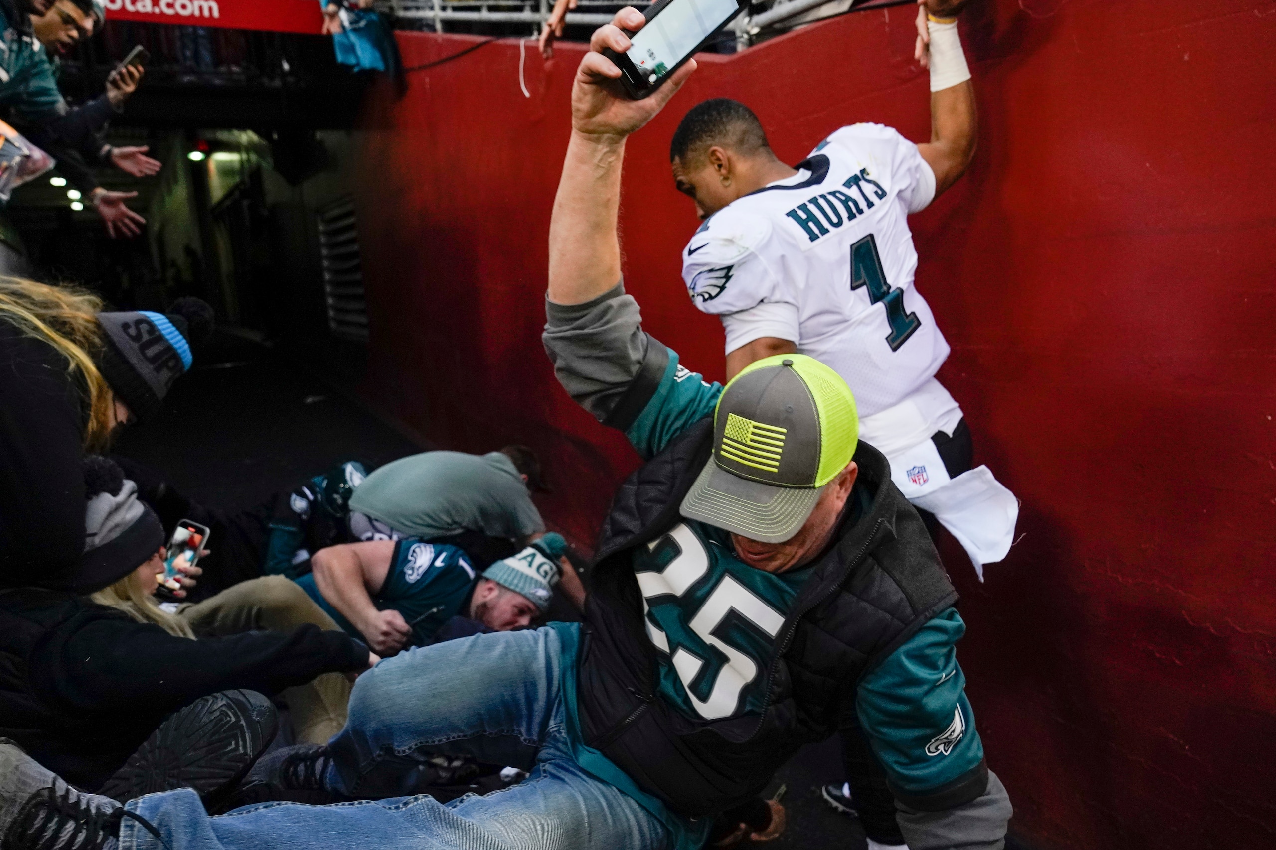 Fans falls onto Philadelphia Eagles quarterback Jalen Hurts (1) after a railing collapsed following the end of an NFL football game, Sunday, Jan. 2, 2022, in Landover, Md. Philadelphia won 20-16. (AP Photo/Alex Brandon) Fans falls onto Philadelphia Eagles quarterback Jalen Hurts (1) after a railing collapsed following the end of an NFL football game, Sunday, Jan. 2, 2022, in Landover, Md. Philadelphia won 20-16. (AP Photo/Alex Brandon)