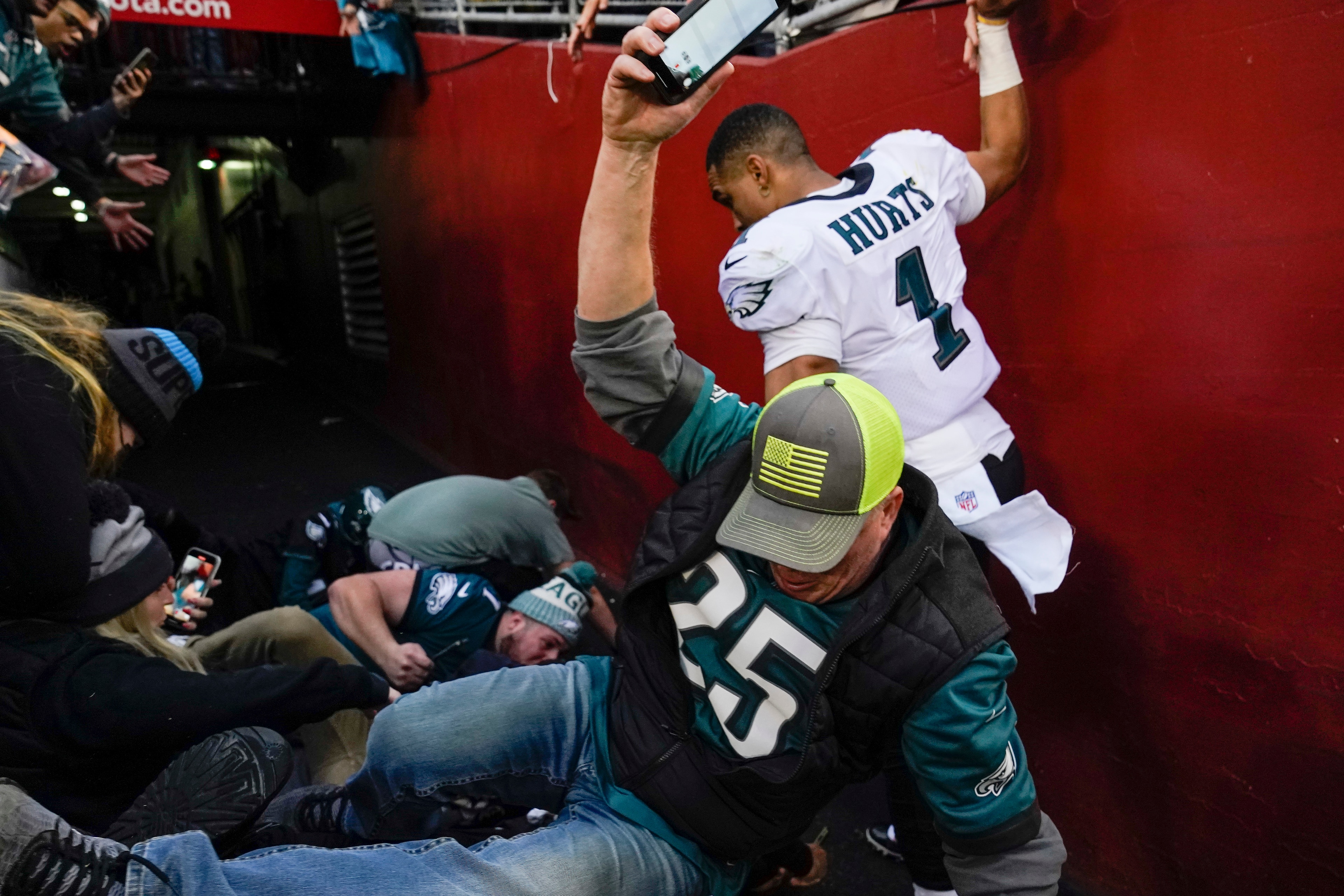 Fans falls onto Philadelphia Eagles quarterback Jalen Hurts (1) after a railing collapsed following the end of an NFL football game, Sunday, Jan. 2, 2022, in Landover, Md. Philadelphia won 20-16. (AP Photo/Alex Brandon)