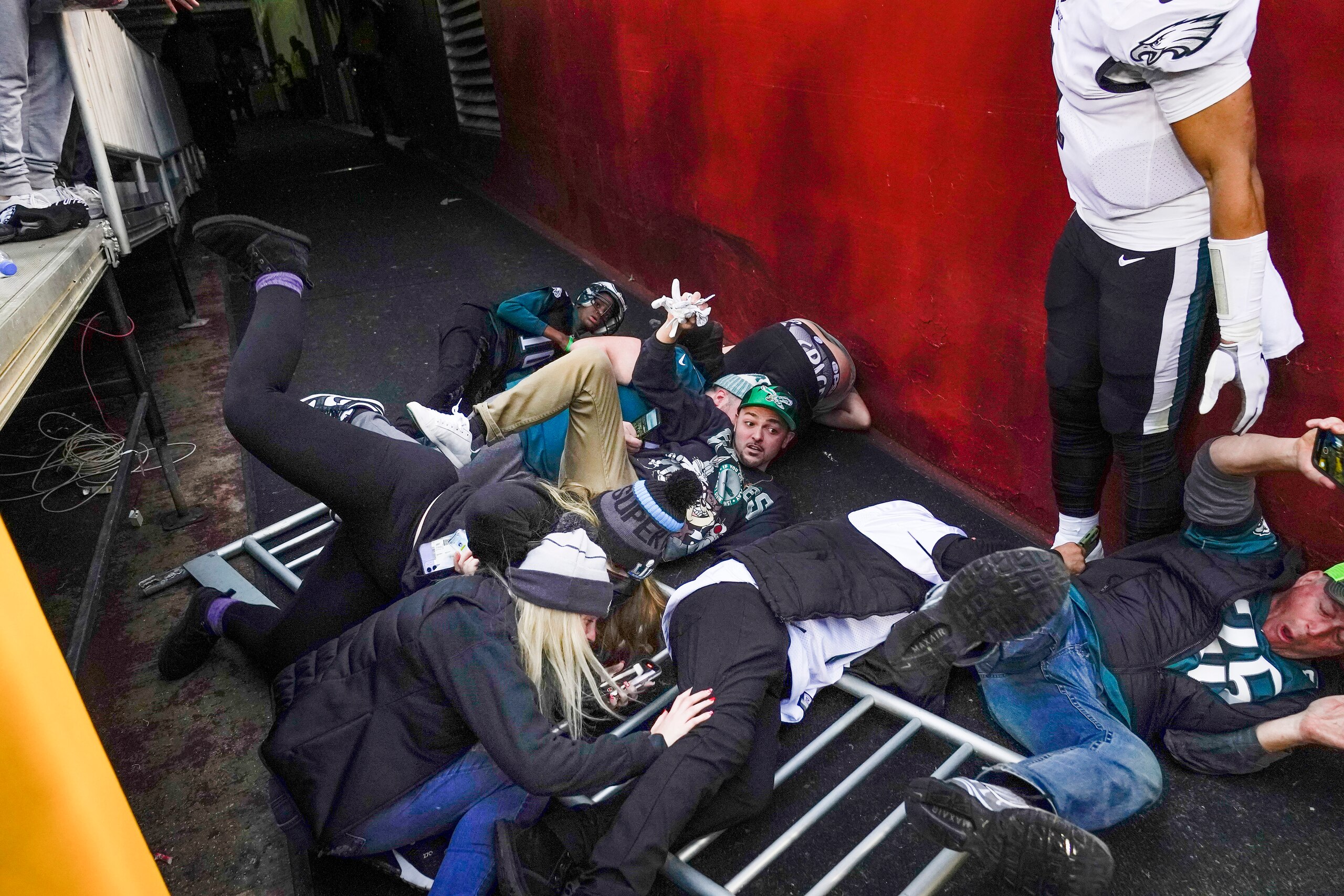 Fans lay on the ground after a railing collapsed causing them to fall towards Philadelphia Eagles quarterback Jalen Hurts (1) at the end of an NFL football game, Sunday, Jan. 2, 2022, in Landover, Md. Philadelphia won 20-16. (AP Photo/Alex Brandon)