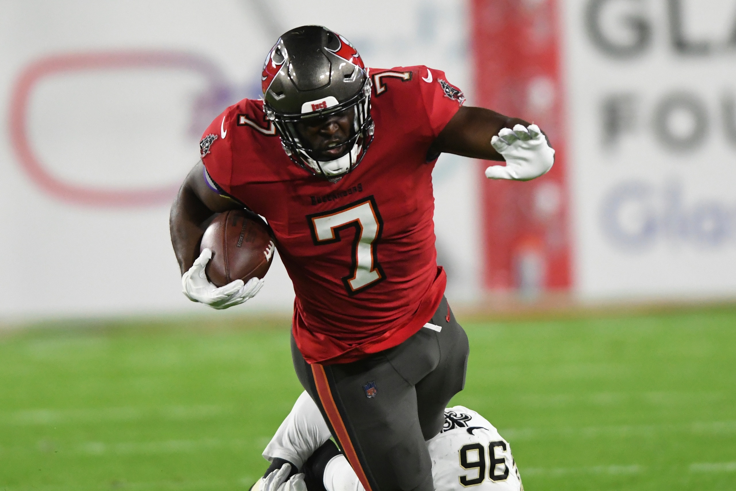 Tampa Bay Buccaneers running back Leonard Fournette (7) gets tripped up by New Orleans Saints defensive back Jordan Miller (36) during the first half of an NFL football game Sunday, Dec. 19, 2021, in Tampa, Fla. (AP Photo/Jason Behnken)
