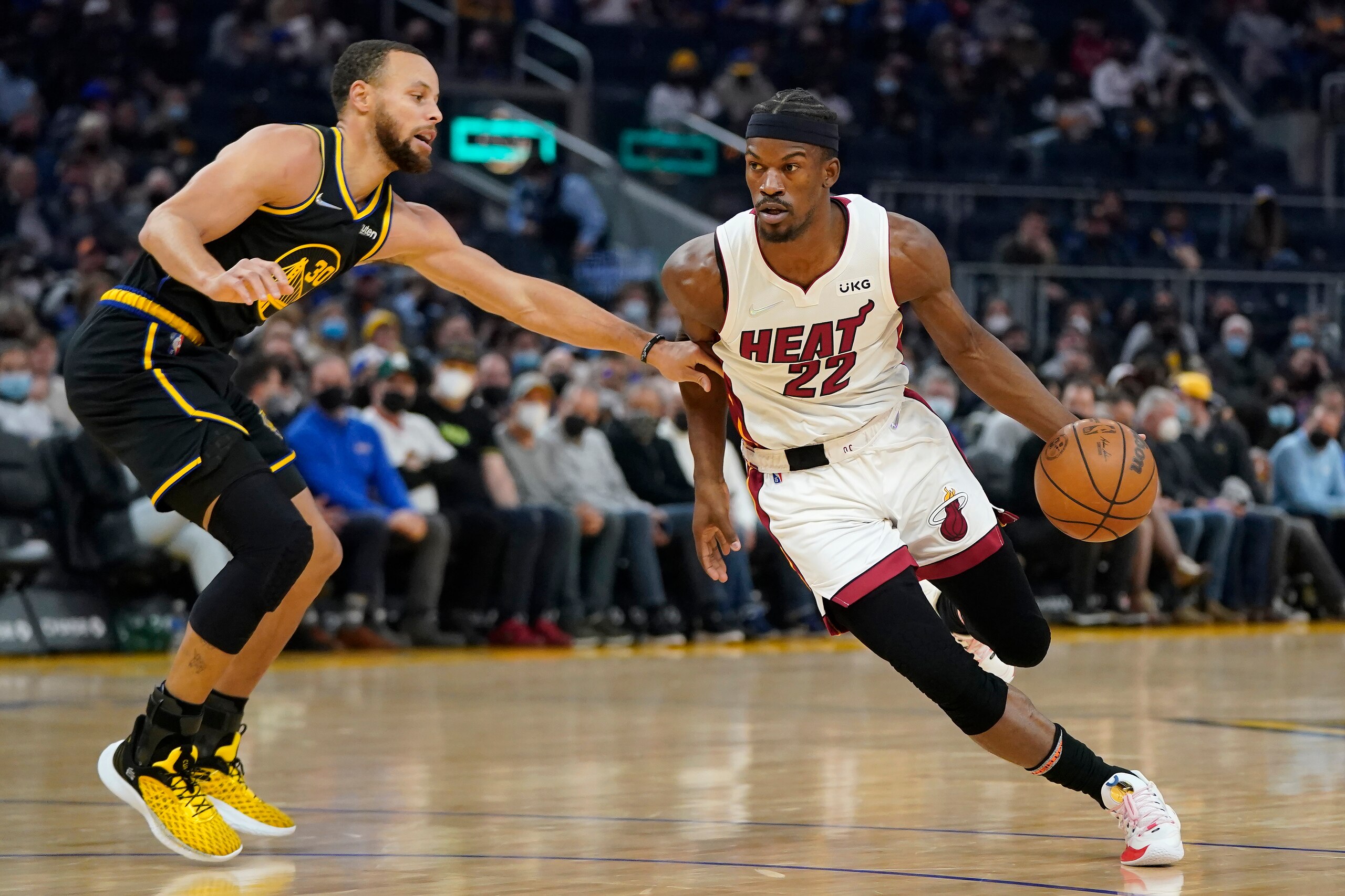 Miami Heat forward Jimmy Butler (22) drives to the basket against Golden State Warriors guard Stephen Curry during the first half of an NBA basketball game in San Francisco, Monday, Jan. 3, 2022. (AP Photo/Jeff Chiu)