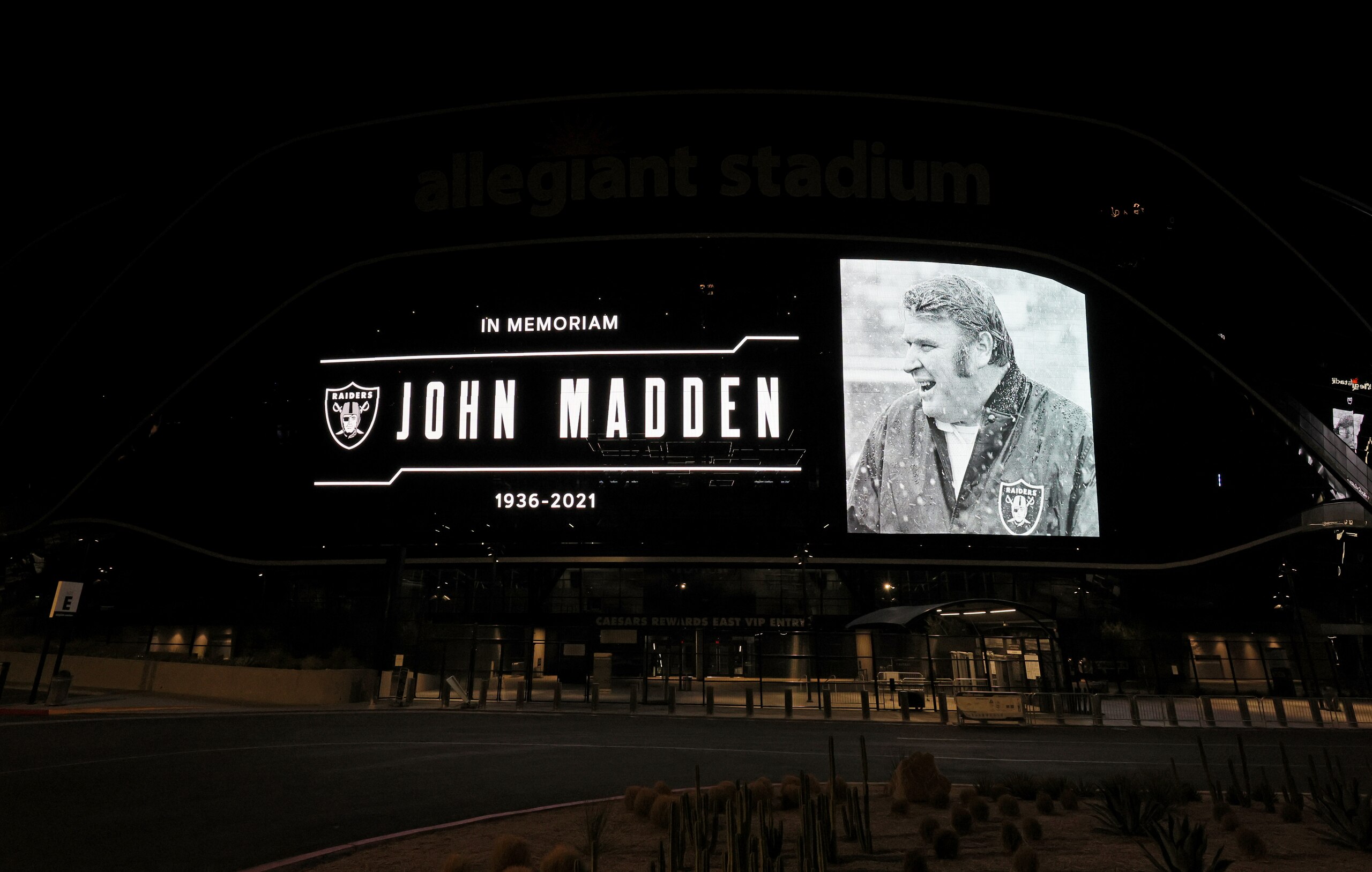 LAS VEGAS, NEVADA - DECEMBER 28:  A tribute to former Raiders head coach, Pro Football Hall of Fame member and broadcaster John Madden is displayed on the side of Allegiant Stadium, home of the Las Vegas Raiders, after news of his death at the age of 85 on December 28, 2021 in Las Vegas, Nevada. Madden coached the Oakland Raiders for 10 seasons and won the team's first championship with a win over the Minnesota Vikings in Super Bowl XI in 1977. Owner and managing general partner Mark Davis of the Las Vegas Raiders lit the Al Davis Memorial Torch inside the stadium before the organization turned off all the exterior lights, except for the memorial message, in honor of Madden.  (Photo by Ethan Miller/Getty Images)