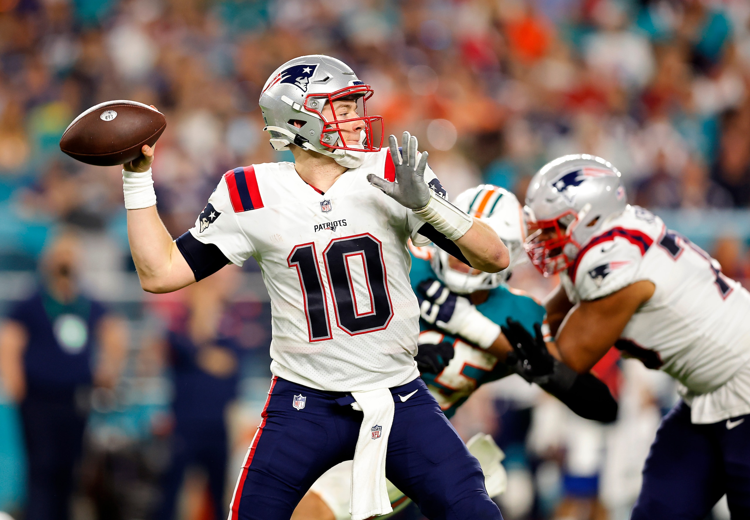 MIAMI GARDENS, FLORIDA - JANUARY 09: Mac Jones #10 of the New England Patriots delivers a pass over the defense of the Miami Dolphins in the second half of the game at Hard Rock Stadium on January 09, 2022 in Miami Gardens, Florida. (Photo by Michael Reaves/Getty Images)