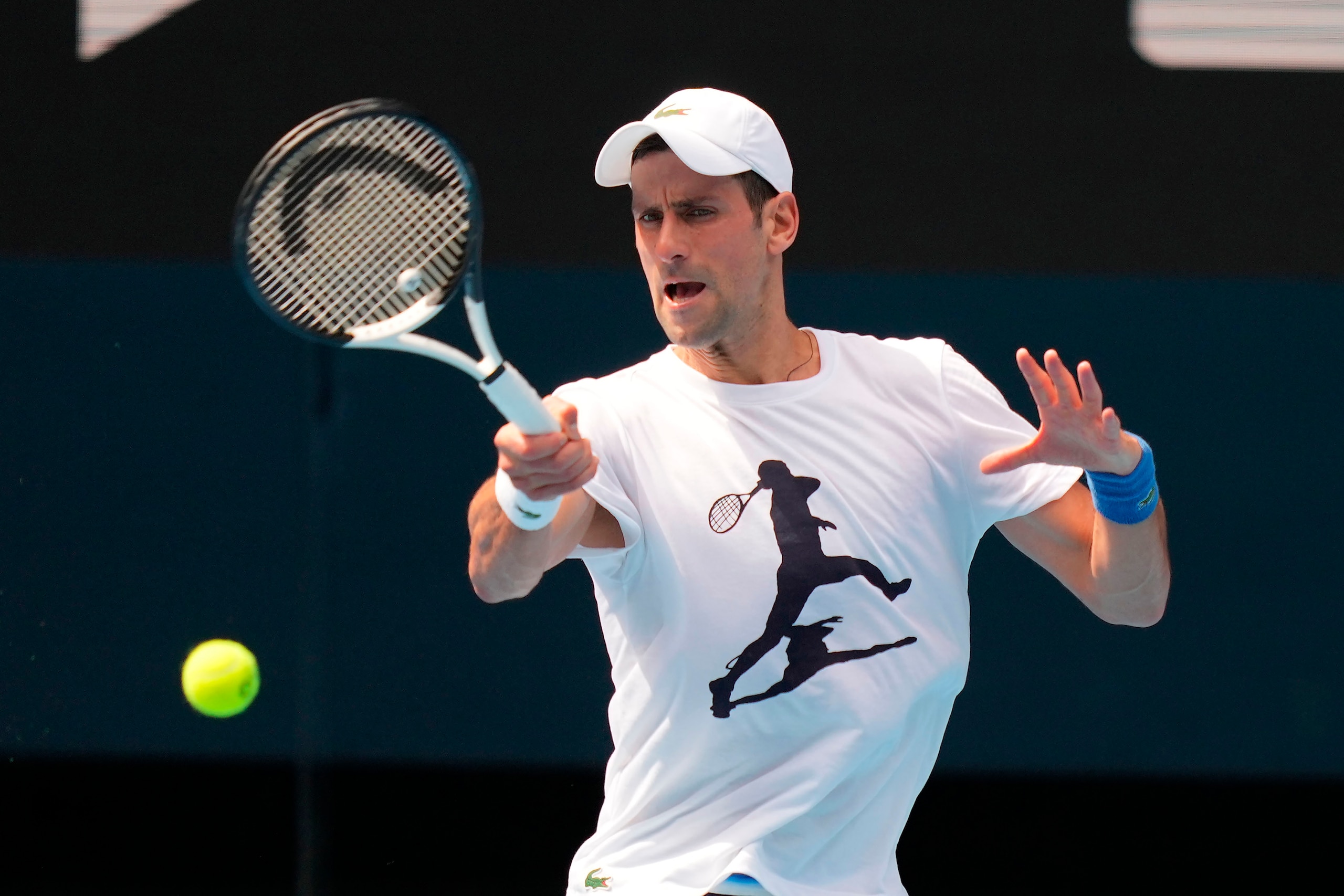 In this photo supplied by Tennis Australia, defending champion Serbia's Novak Djokovic practices in the Rod Laver Arena ahead of the Australian Open at Melbourne Park in Melbourne, Australia, Tuesday, Jan. 11, 2022. The prime ministers of Australia and Serbia have discussed Novak Djokovic's precarious visa after the top-ranked Serbian tennis star won a court battle to compete in the Australian Open but still faces the threat of deportation because he is not vaccinated against COVID-19. (Scott Barbour/Tennis Australia via AP)