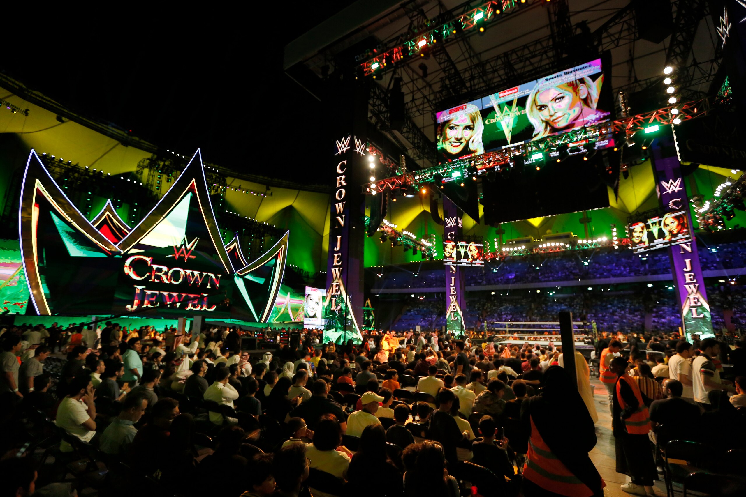 Saudi wrestling fans wait to watch World Wrestling Entertainment "WWE" stars Lacey Evans and Natalya Neidhart, on top screen, as they play the first-ever women's wrestling match in Saudi at King Fahd International Stadium in Riyadh, Saudi Arabia, Thursday, Oct. 31, 2019. (AP Photo/Amr Nabil)