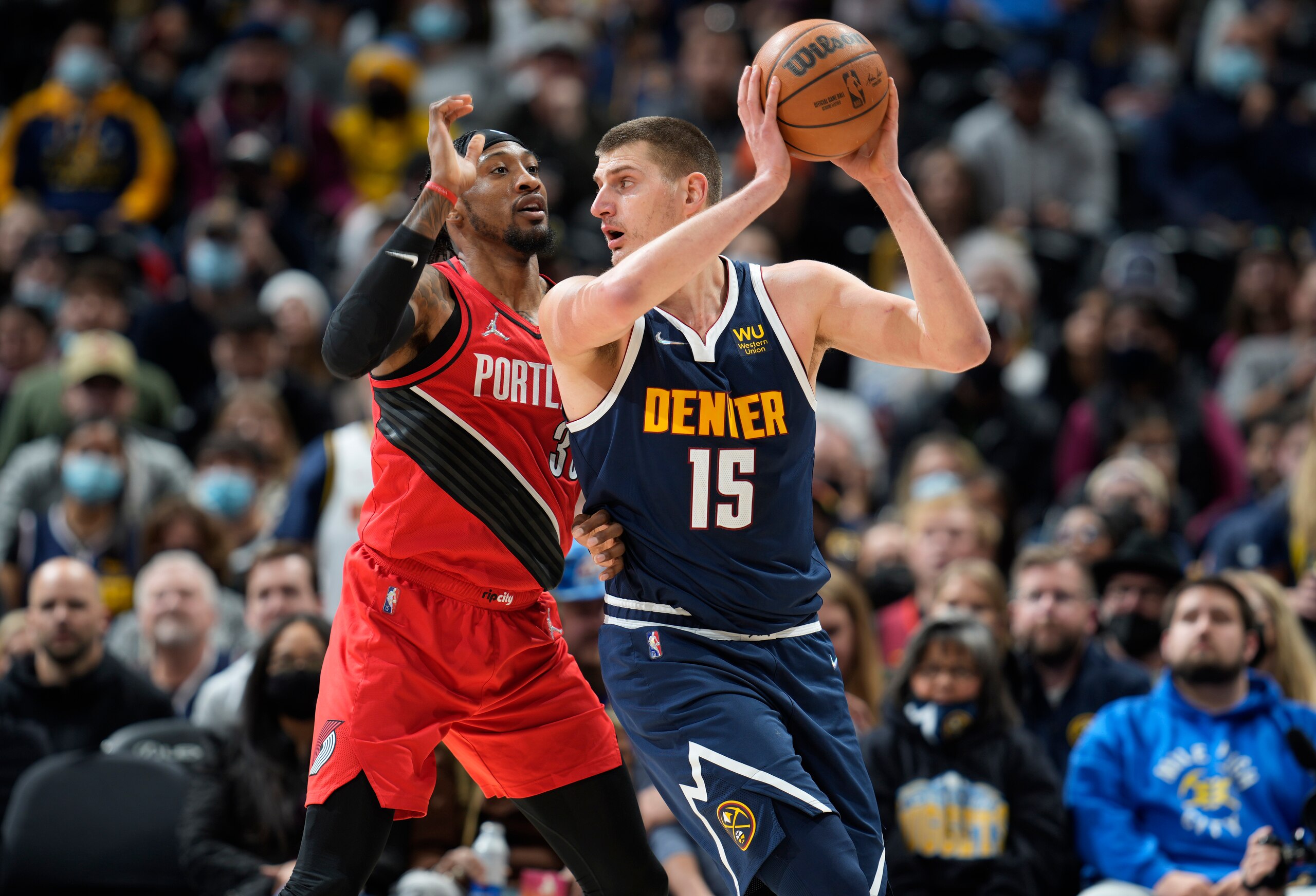 Denver Nuggets center Nikola Jokic, right, looks to pass the ball as Portland Trail Blazers forward Robert Covington defends in the first half of an NBA basketball game Thursday, Jan. 13, 2022, in Denver. (AP Photo/David Zalubowski)