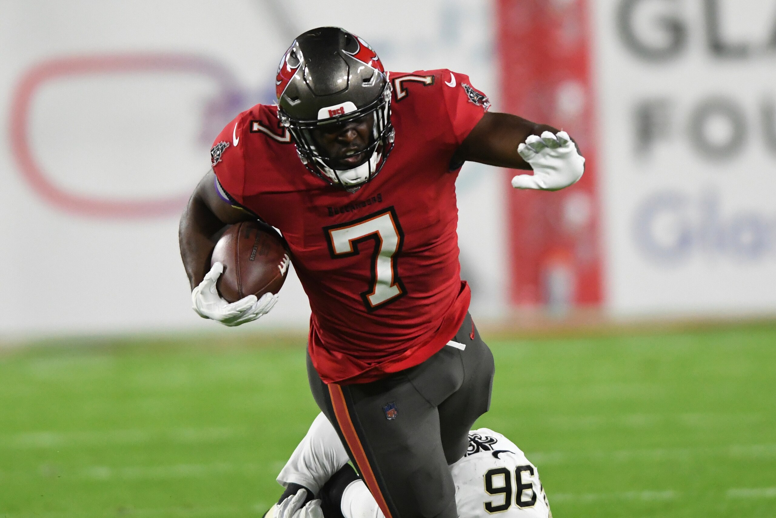 Tampa Bay Buccaneers running back Leonard Fournette (7) gets tripped up by New Orleans Saints defensive back Jordan Miller (36) during the first half of an NFL football game Sunday, Dec. 19, 2021, in Tampa, Fla. (AP Photo/Jason Behnken)