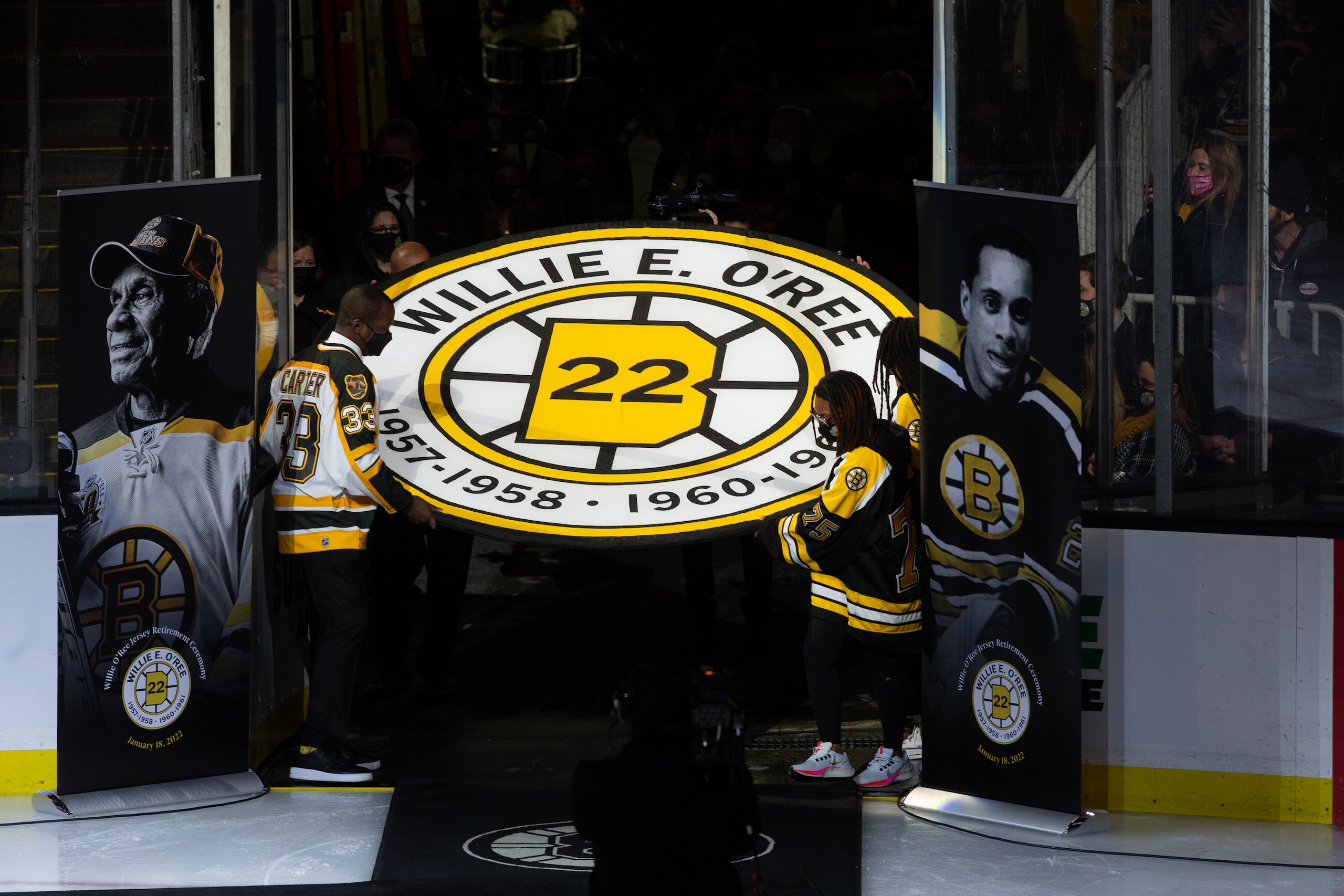 BOSTON, MA - JANUARY 18: Anson Carter helps carry the banner as former Boston Bruins player Willie O'Ree has his No. 22 jersey retired prior to the game between the Carolina Hurricanes and the Boston Bruins at the TD Garden on January 18, 2022 in Boston, Massachusetts. (Photo by Rich Gagnon/Getty Images)