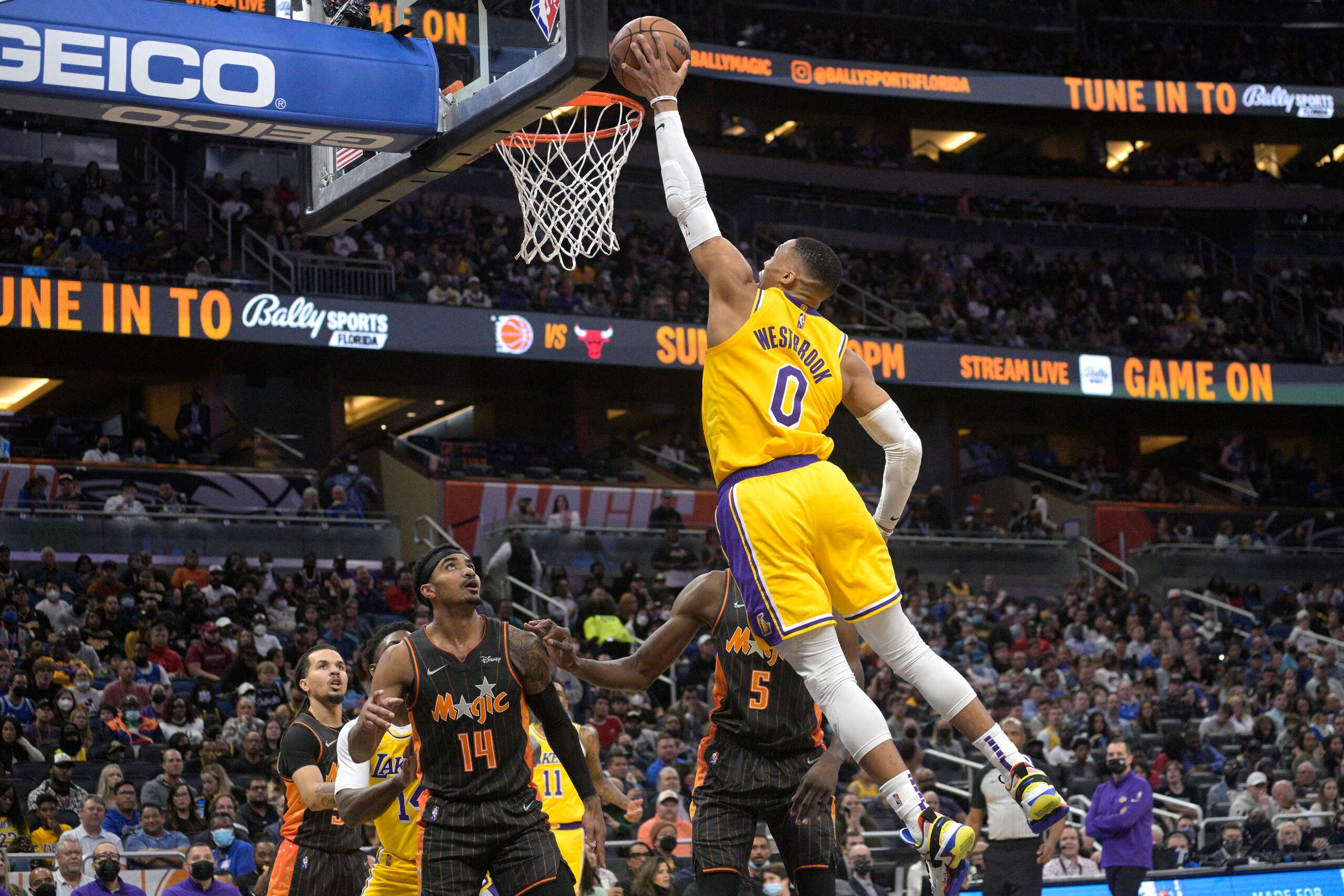 Los Angeles Lakers guard Russell Westbrook (0) goes up for a dunk in front of Orlando Magic guard Gary Harris (14) and center Mo Bamba (5) during the first half of an NBA basketball game, Friday, Jan. 21, 2022, in Orlando, Fla. (AP Photo/Phelan M. Ebenhack)