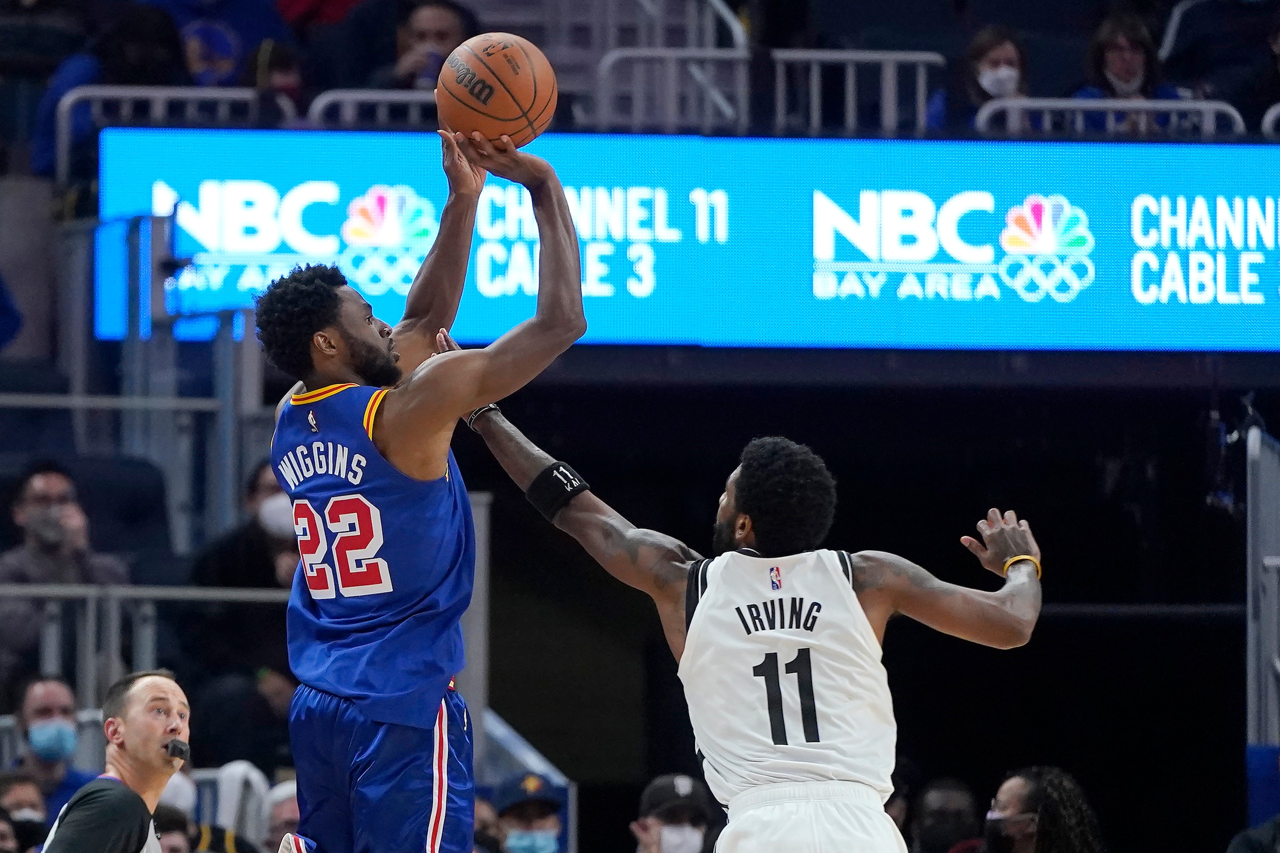 Golden State Warriors forward Andrew Wiggins (22) shoots a 3-point basket over Brooklyn Nets guard Kyrie Irving (11) during the first half of an NBA basketball game in San Francisco, Saturday, Jan. 29, 2022. (AP Photo/Jeff Chiu)