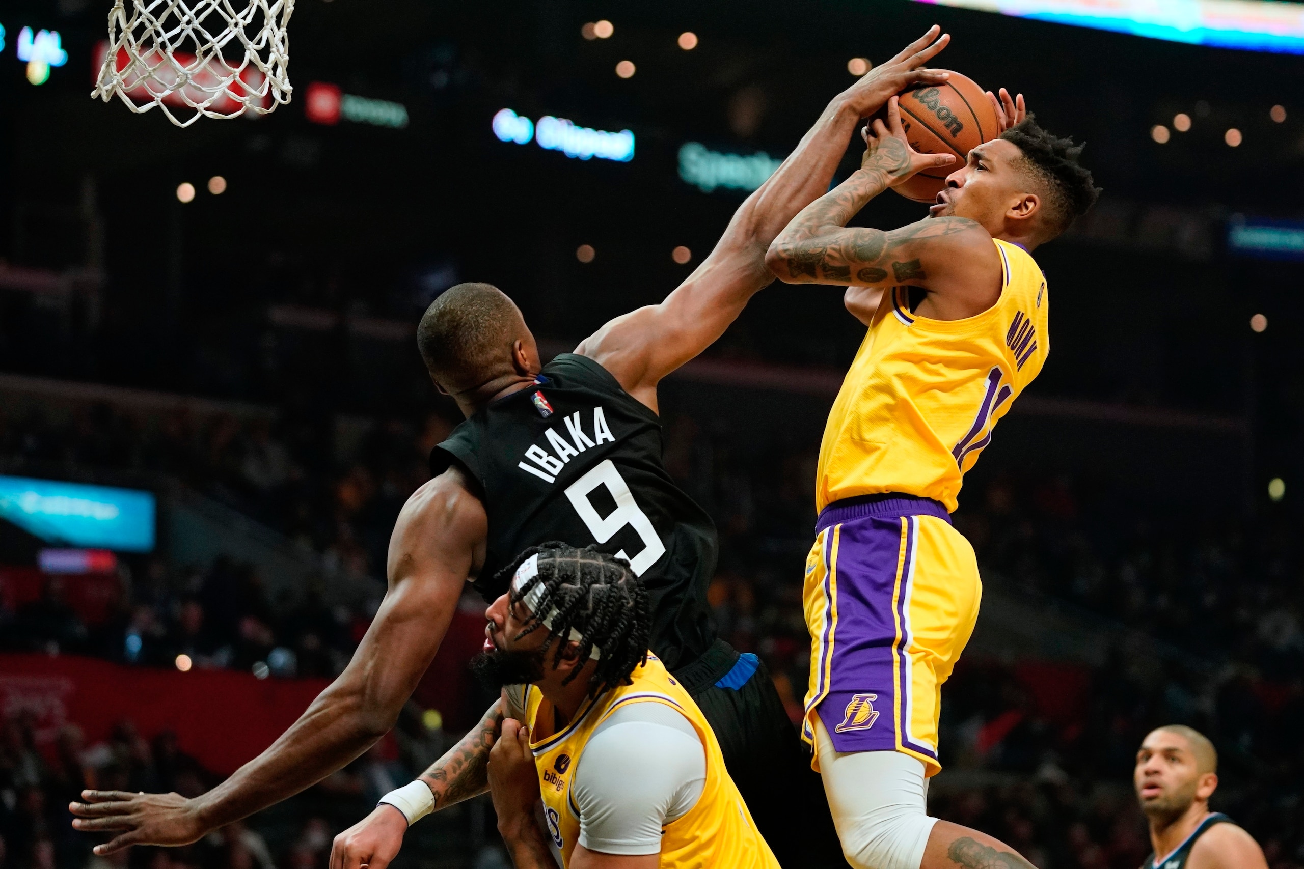 Los Angeles Lakers guard Malik Monk, right, shoots as Los Angeles Clippers center Serge Ibaka, left, defends while forward Anthony Davis stands by during the first half of an NBA basketball game Thursday, Feb. 3, 2022, in Los Angeles. (AP Photo/Mark J. Terrill)