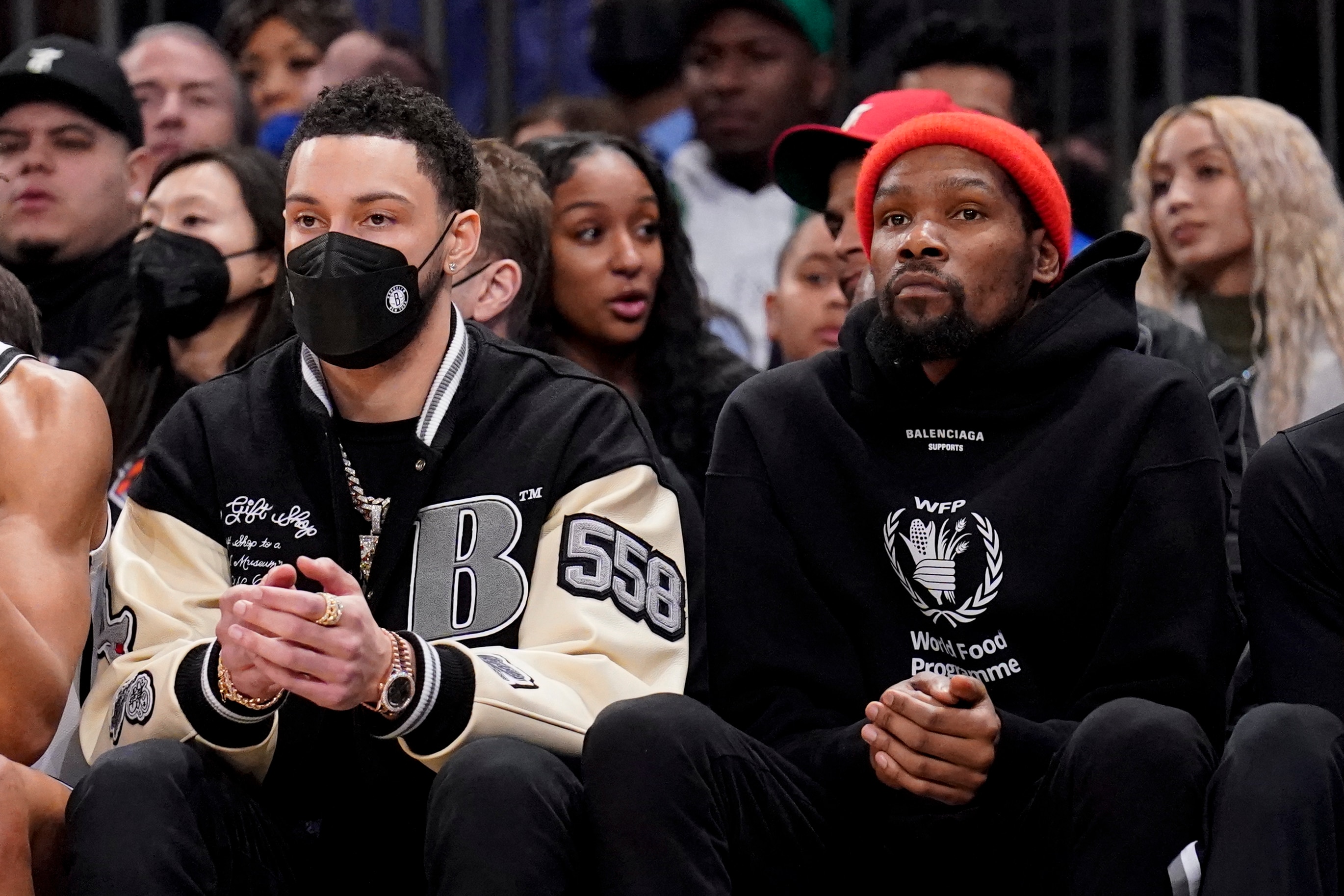 Brooklyn Nets forward Ben Simmons, left, sits with forward Kevin Durant, right, on the bench during the first half of an NBA basketball game against the New York Knicks, Wednesday, Feb. 16, 2022, in New York. (AP Photo/John Minchillo)