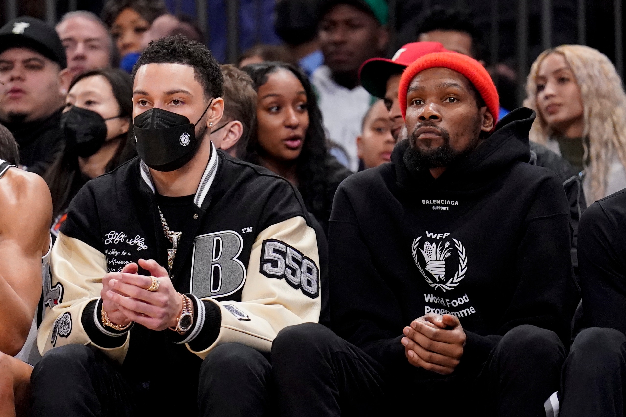 Brooklyn Nets forward Ben Simmons, left, sits with forward Kevin Durant, right, on the bench during the first half of an NBA basketball game against the New York Knicks, Wednesday, Feb. 16, 2022, in New York. (AP Photo/John Minchillo)