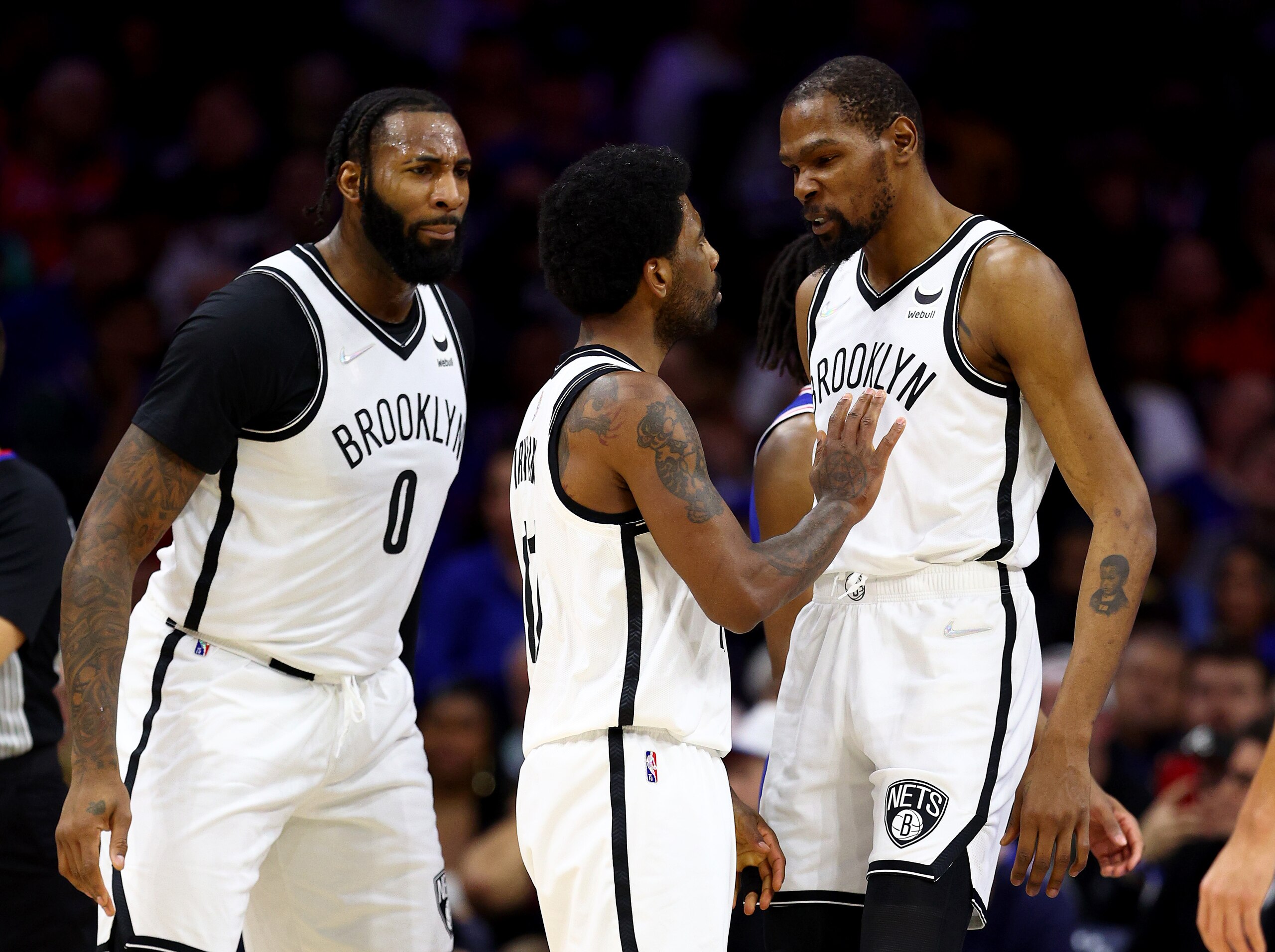 PHILADELPHIA, PENNSYLVANIA - MARCH 10:  Andre Drummond #0, Kyrie Irving #11 and Kevin Durant #7 of the Brooklyn Nets react in the first half against the Philadelphia 76ers at Wells Fargo Center on March 10, 2022 in Philadelphia, Pennsylvania. NOTE TO USER: User expressly acknowledges and agrees that, by downloading and or using this photograph, User is consenting to the terms and conditions of the Getty Images License Agreement. (Photo by Elsa/Getty Images)