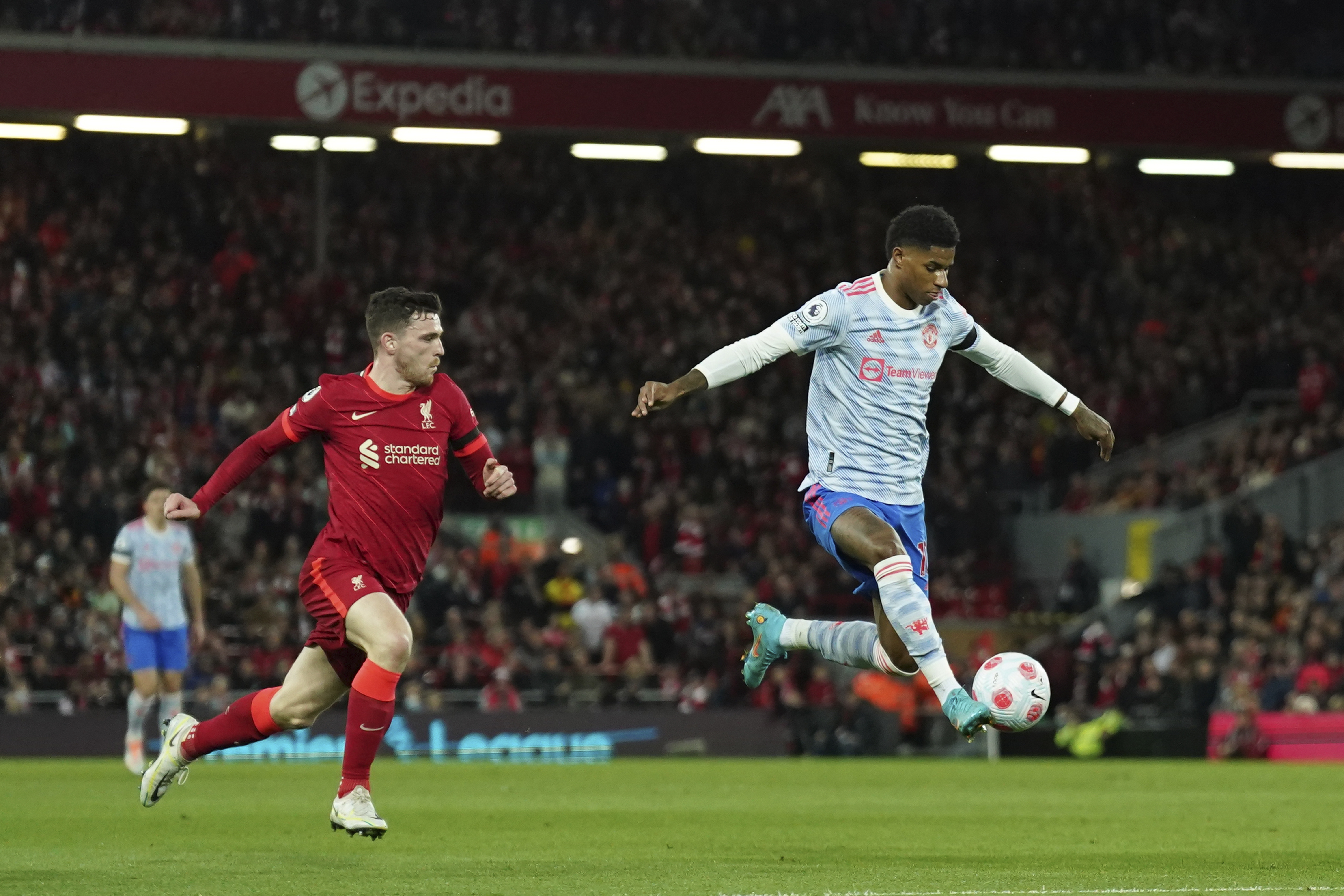 Manchester United's Marcus Rashford, right, controls the ball past Liverpool's Andrew Robertson during the English Premier League soccer match between Liverpool and Manchester United at Anfield stadium in Liverpool, England, Tuesday, April 19, 2022. (AP Photo/Jon Super)