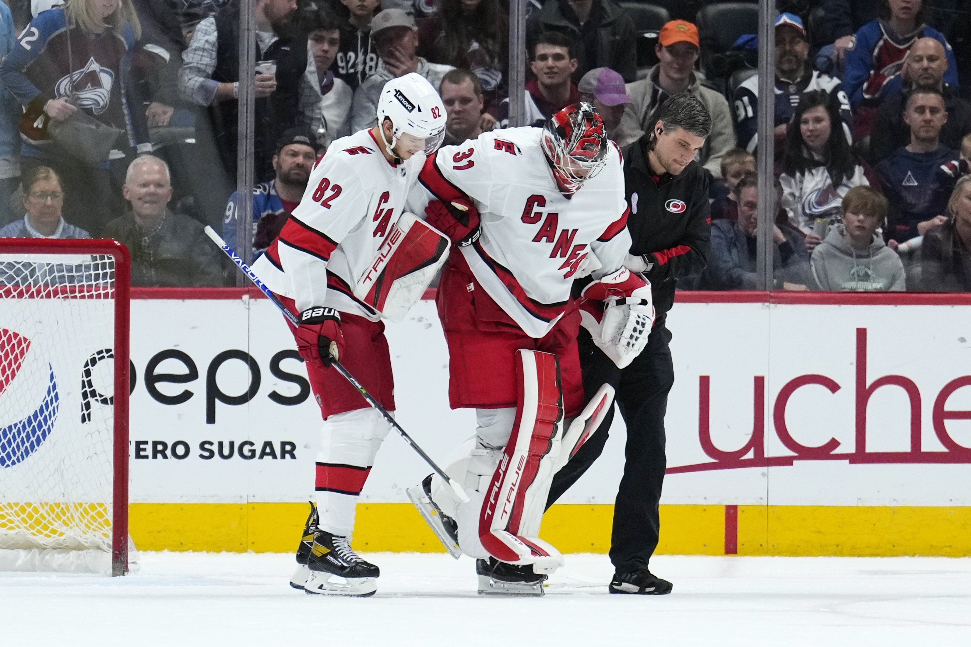 Carolina Hurricanes goaltender Frederik Andersen (31) is helped off the ice by Jesperi Kotkaniemi (82) and a trainer during the third period of the team's NHL hockey game against the Colorado Avalanche on Saturday, April 16, 2022, in Denver. (AP Photo/Jack Dempsey)