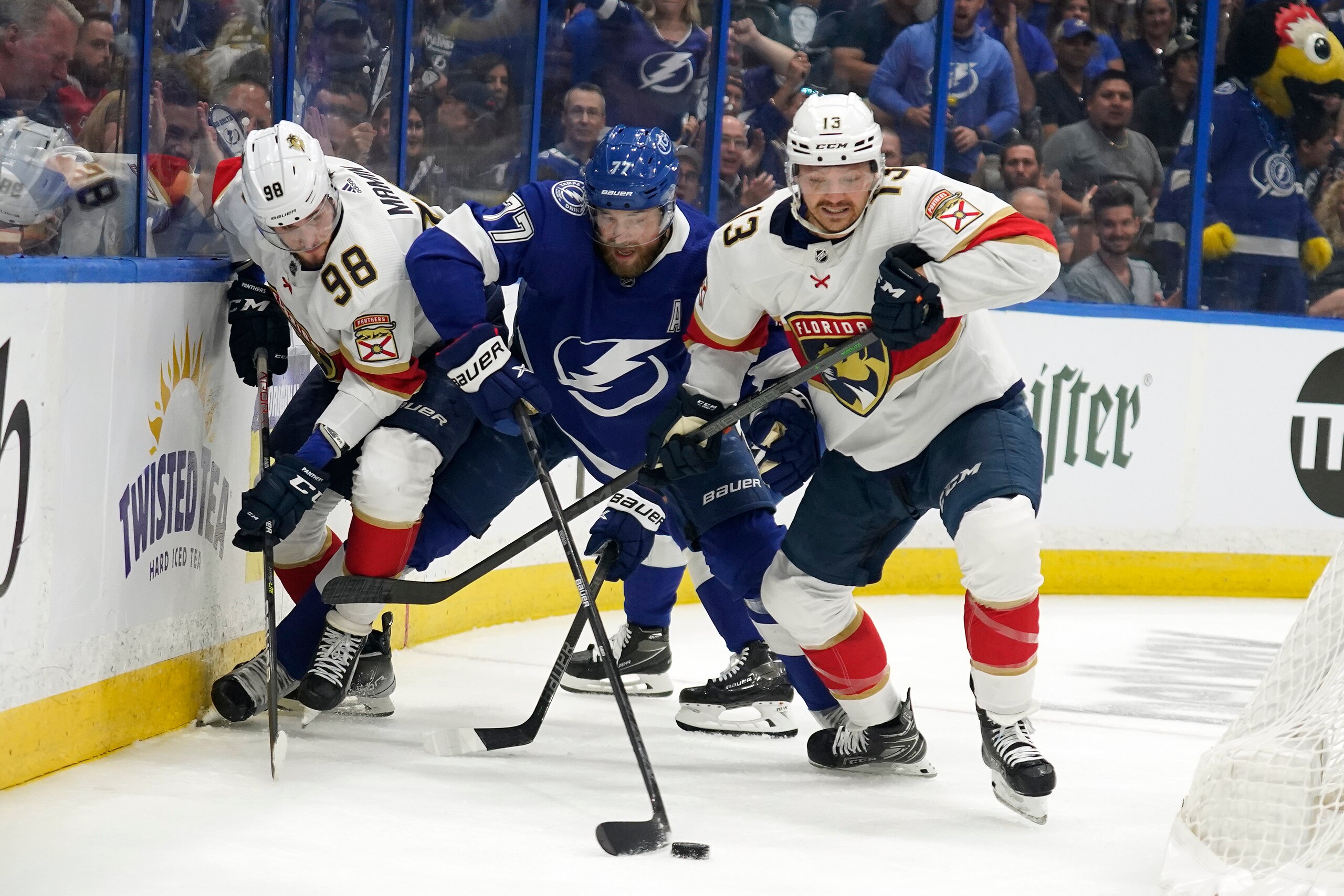 Tampa Bay Lightning defenseman Victor Hedman (77) puches the puck away from Florida Panthers center Sam Reinhart (13) and center Maxim Mamin (98) during the first period in Game 3 of an NHL hockey second-round playoff series Sunday, May 22, 2022, in Tampa, Fla. (AP Photo/Chris O'Meara)