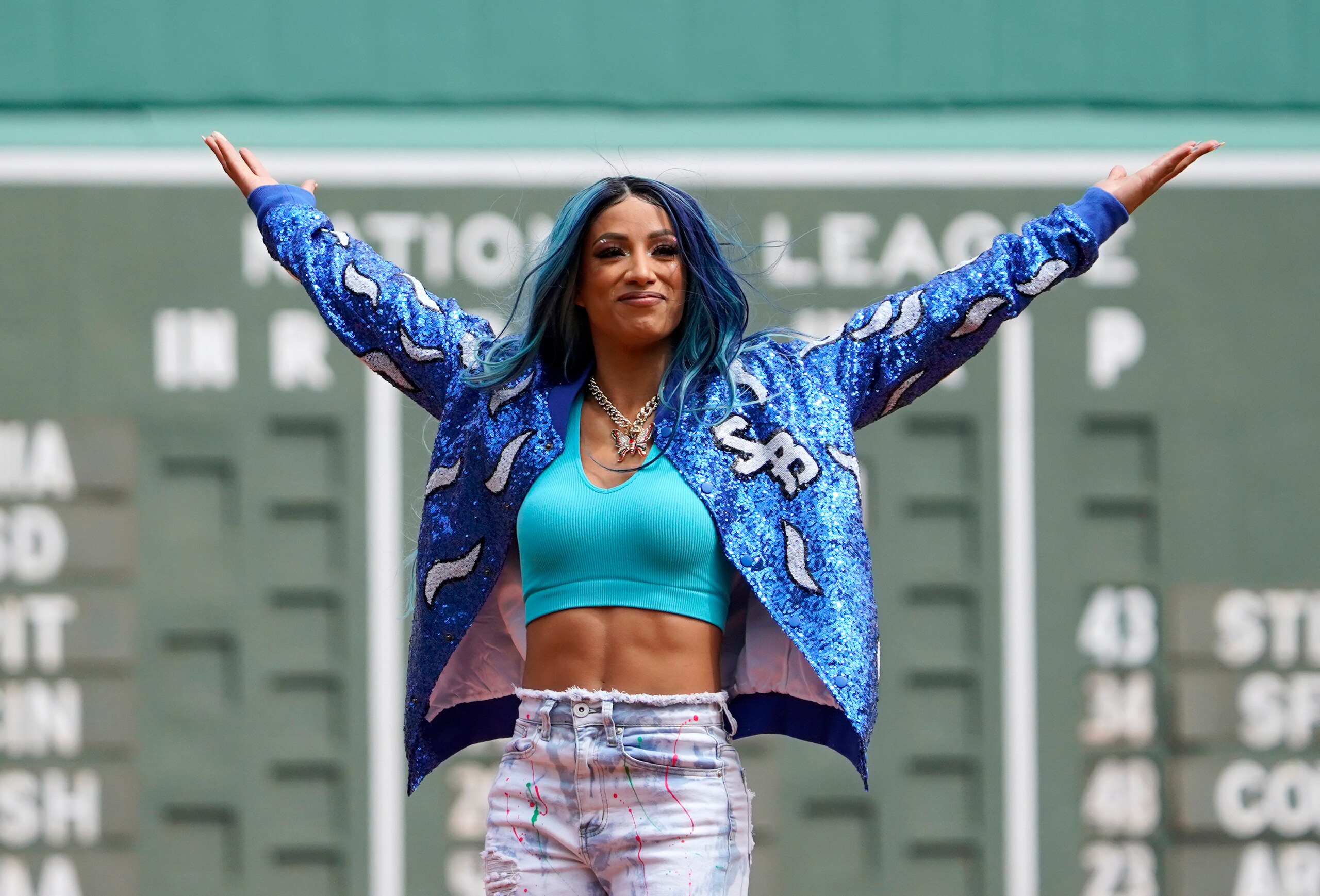 WWE wrestler Sasha Banks reacts before throwing out the first pitch before the start of baseball game between the Boston Red Sox and the Chicago White Sox at Fenway Park, Sunday, May 8, 2022, in Boston. (AP Photo/Mary Schwalm)
