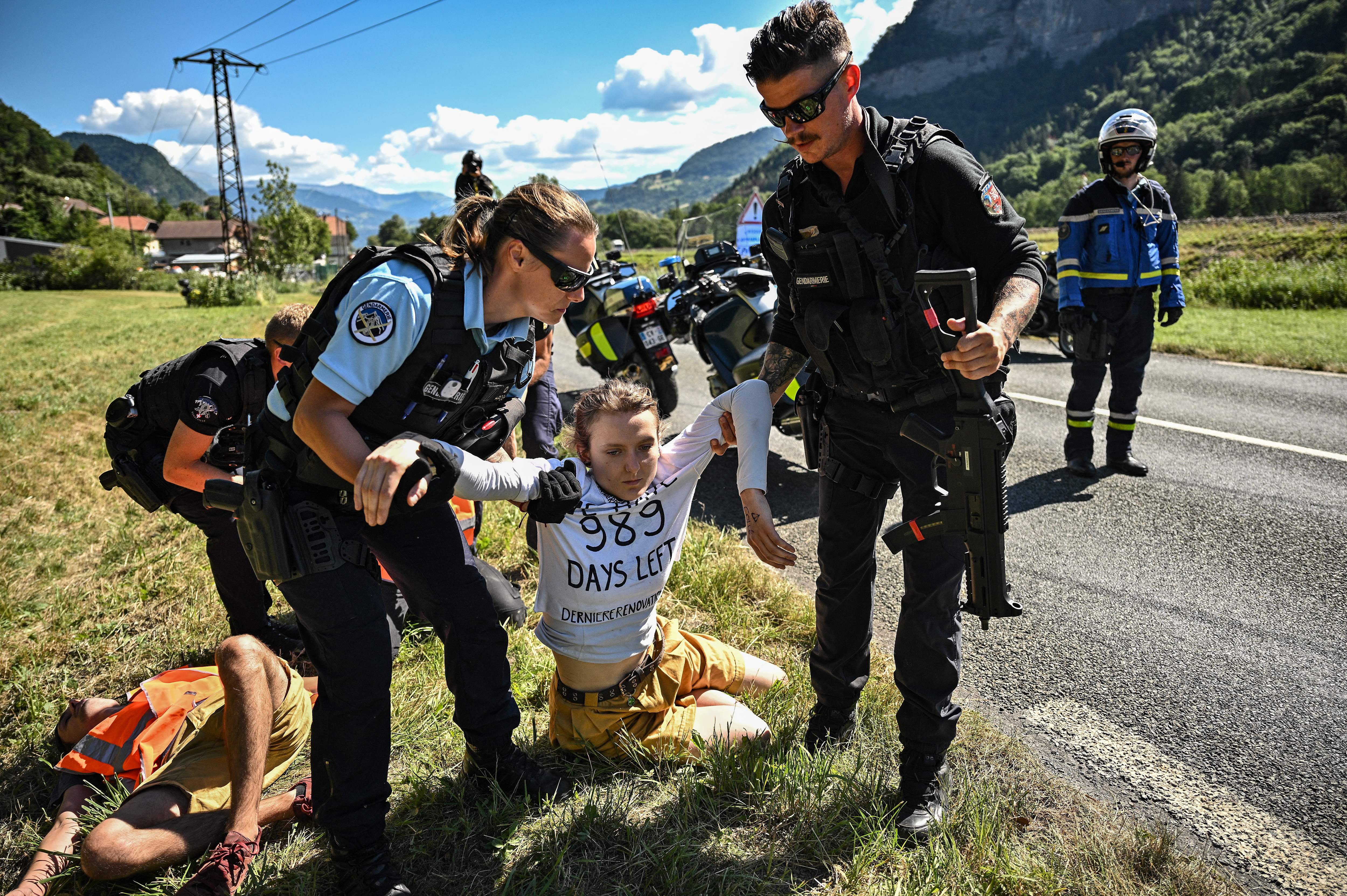 French gendarmes remove environmental protestors from the race route as their protest action temporarily immobilized the pack of riders during the 10th stage of the 109th edition of the Tour de France cycling race, 148,1 km between Morzine and Megeve, in the French Alps, on July 12, 2022. (Photo by Marco BERTORELLO / AFP) (Photo by MARCO BERTORELLO/AFP via Getty Images)