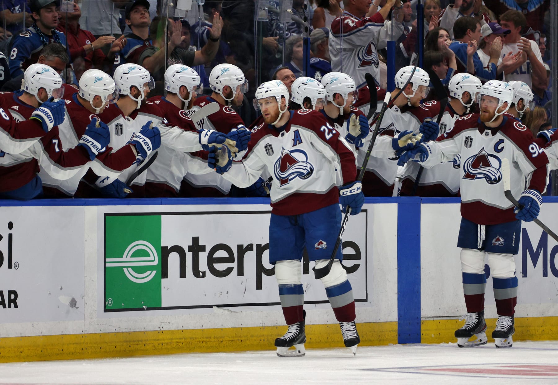 TAMPA, FLORIDA - JUNE 26: Nathan MacKinnon #29 and Gabriel Landeskog #92 of the Colorado Avalanche skate by the bench to celebrate with teammates after MacKinnon scored in the second period of Game Six of the 2022 Stanley Cup Final against the Tampa Bay Lightning at Amalie Arena on June 26, 2022 in Tampa, Florida. (Photo by Dave Sandford/NHLI via Getty Images)