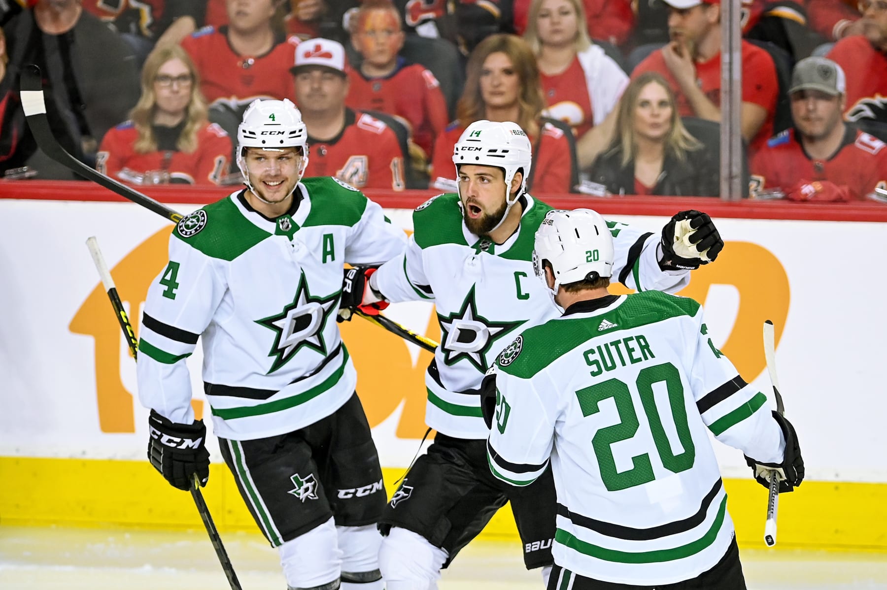 CALGARY, AB - MAY 15: Dallas Stars Left Wing Jamie Benn (14) celebrates with Dallas Stars Defenceman Miro Heiskanen (4) and Dallas Stars Defenceman Ryan Suter (20) after scoring a goal during the first period of game 7 of the first round of the NHL Stanley Cup Playoffs between the Calgary Flames and the Dallas Stars on May 15, 2022, at the Scotiabank Saddledome in Calgary, AB. (Photo by Brett Holmes/Icon Sportswire via Getty Images)