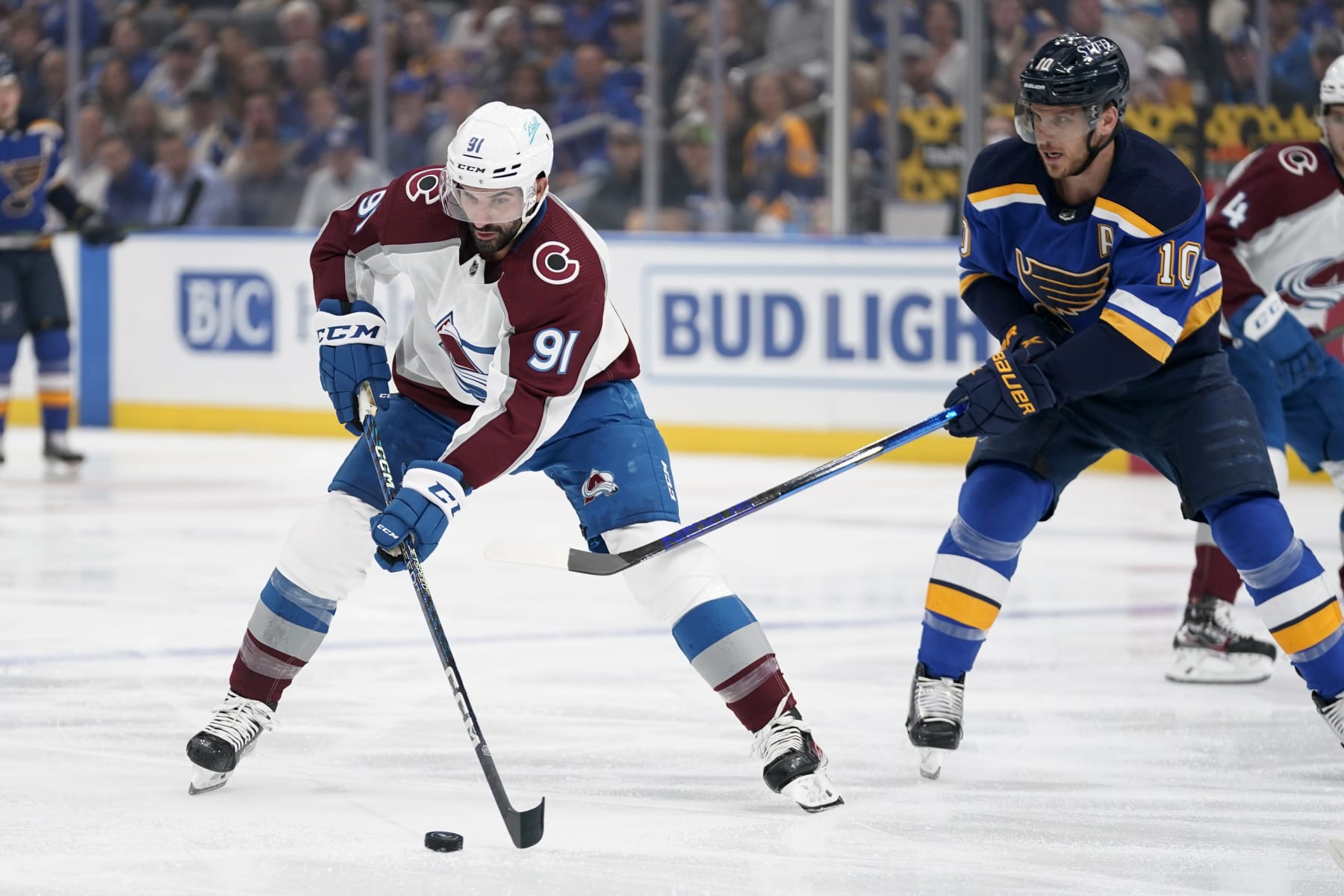 Colorado Avalanche's Nazem Kadri (91) brings the puck down the ice as St. Louis Blues' Brayden Schenn (10) defends during the first period in Game 4 of an NHL hockey Stanley Cup second-round playoff series Monday, May 23, 2022, in St. Louis. (AP Photo/Jeff Roberson)