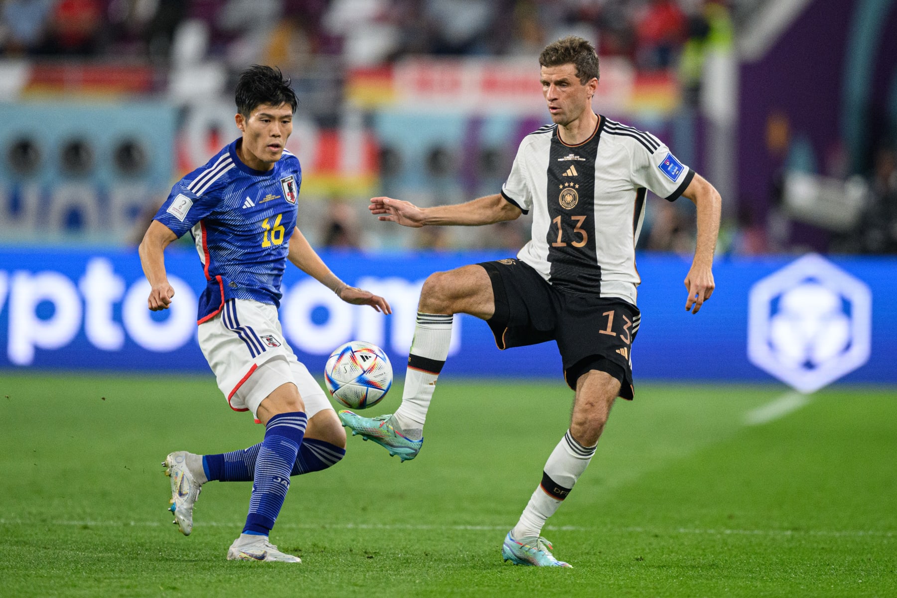 DOHA, QATAR - NOVEMBER 23: Thomas Mueller (R) of Germany challenges for the ball with Takehiro Tomiyasu (L) of Japan during the FIFA World Cup Qatar 2022 Group E match between Germany and Japan at Khalifa International Stadium on November 23, 2022 in Doha, Qatar. (Photo by Marvin Ibo Guengoer - GES Sportfoto/Getty Images)