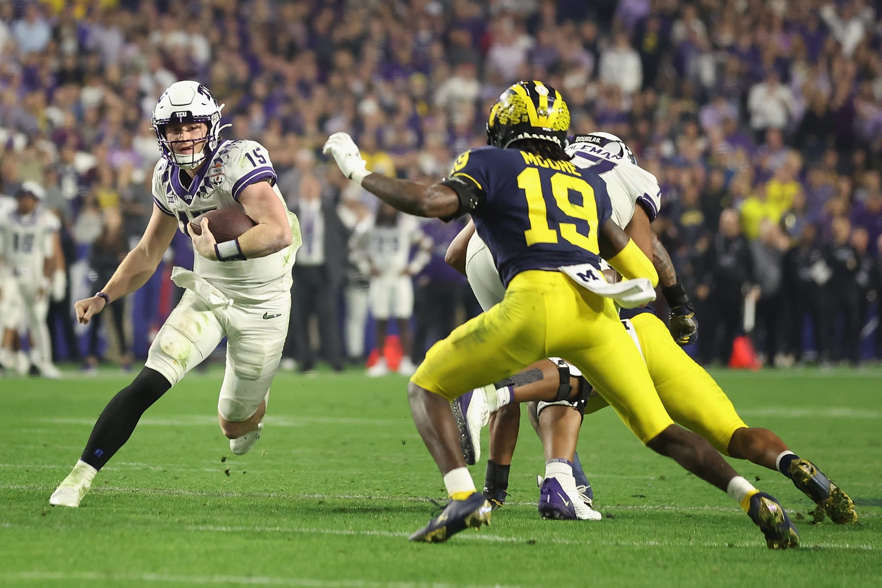 GLENDALE, ARIZONA - DECEMBER 31: Quarterback Max Duggan #15 of the TCU Horned Frogs scrambles with the football against Rod Moore #19 of the Michigan Wolverines during the fourth quarter of the Vrbo Fiesta Bowl at State Farm Stadium on December 31, 2022 in Glendale, Arizona. The Horned Frogs defeated the Wolverines 51-45. (Photo by Christian Petersen/Getty Images)