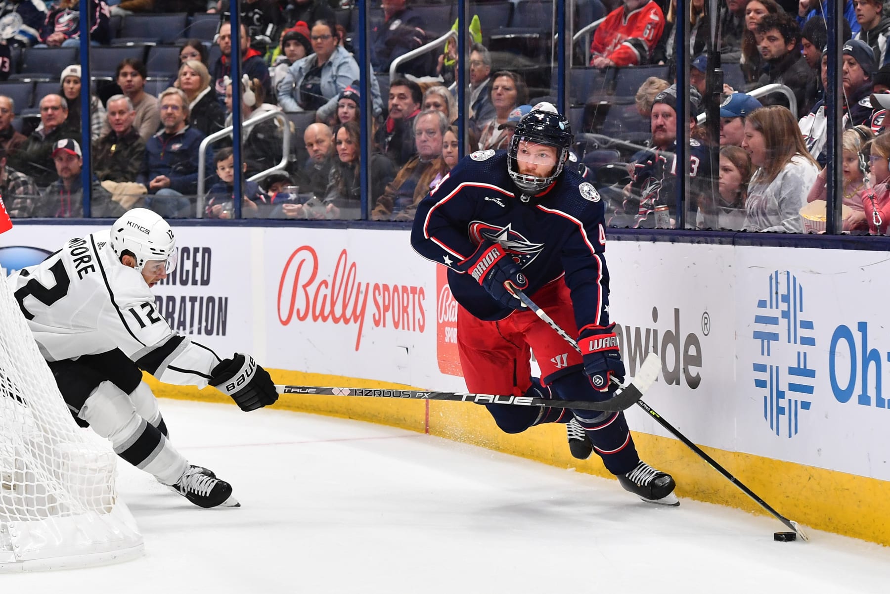 COLUMBUS, OHIO - DECEMBER 11: Vladislav Gavrikov #4 of the Columbus Blue Jackets skates with the puck as Trevor Moore #12 of the Los Angeles Kings defends during the first period of a game at Nationwide Arena on December 11, 2022 in Columbus, Ohio. (Photo by Ben Jackson/NHLI via Getty Images)