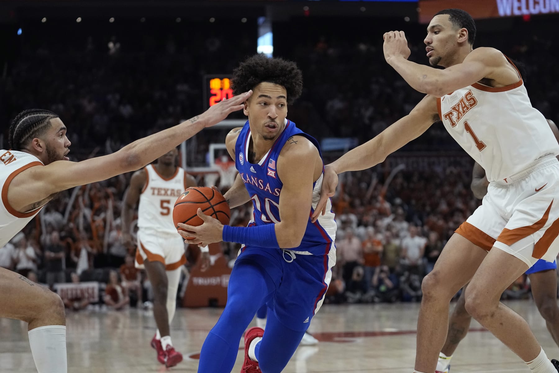 Kansas forward Jalen Wilson (10) drives between Texas forward Timmy Allen, left, and forward Dylan Disu (1) during the first half of an NCAA college basketball game in Austin, Texas, Saturday, March 4, 2023. (AP Photo/Eric Gay)