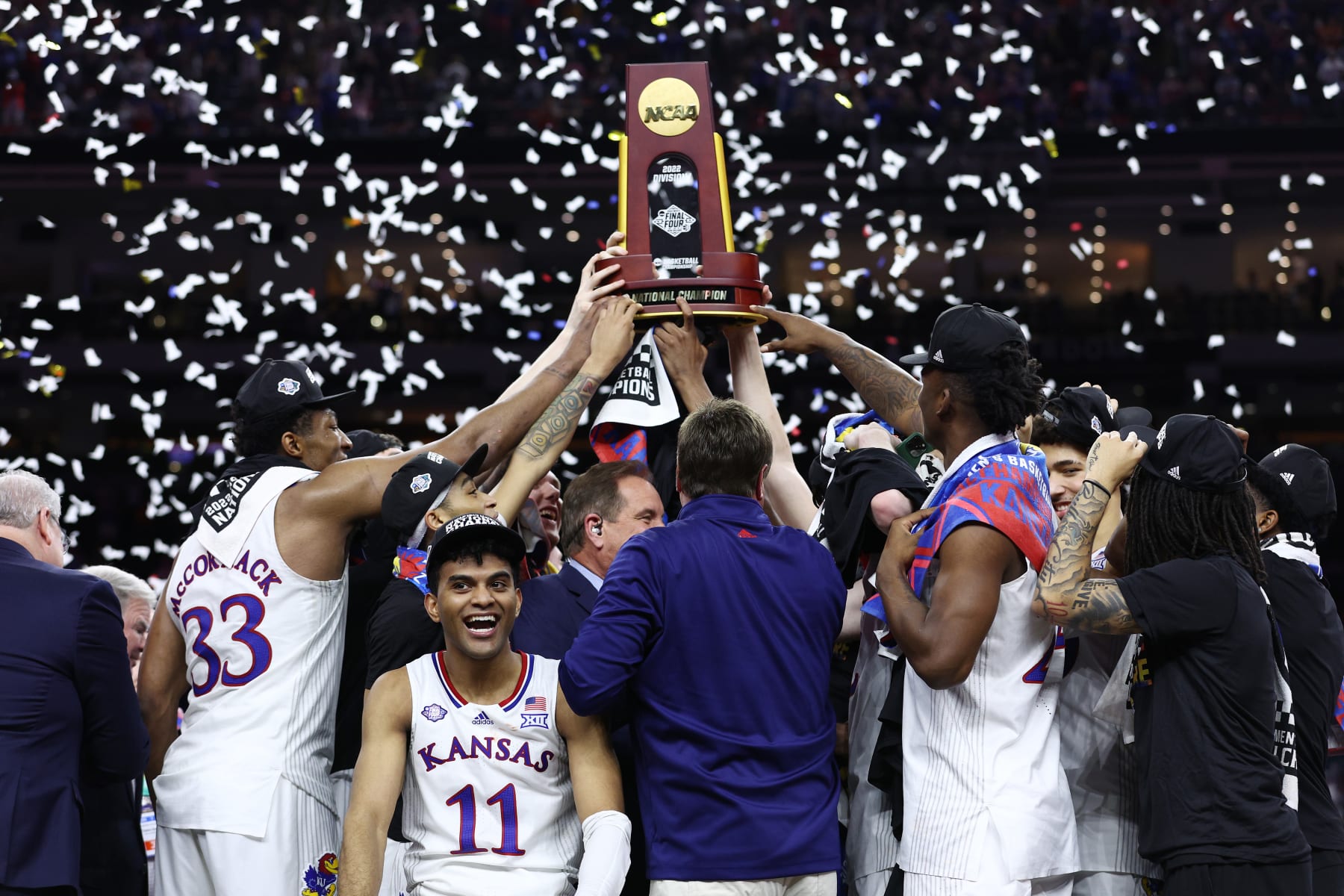 NEW ORLEANS, LOUISIANA - APRIL 04: Remy Martin #11 of the Kansas Jayhawks reacts as Kansas Jayhawks players and coaches hold up the trophy after defeating the North Carolina Tar Heels 72-69 during the 2022 NCAA Men's Basketball Tournament National Championship at Caesars Superdome on April 04, 2022 in New Orleans, Louisiana. (Photo by Tom Pennington/Getty Images)