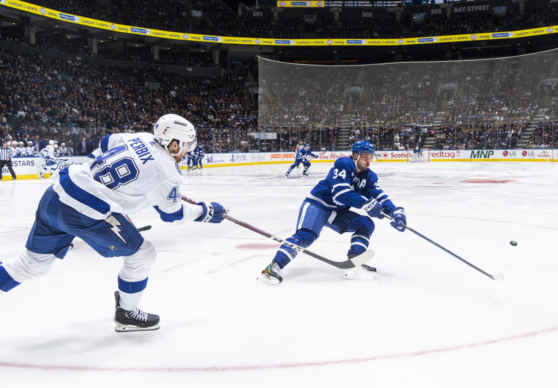TORONTO, ON - DECEMBER 20: Nick Perbix #48 of the Tampa Bay Lightning passes the puck against Auston Matthews #34 of the Toronto Maple Leafs during the third period at the Scotiabank Arena on December 20, 2022 in Toronto, Ontario, Canada. (Photo by Mark Blinch/NHLI via Getty Images)