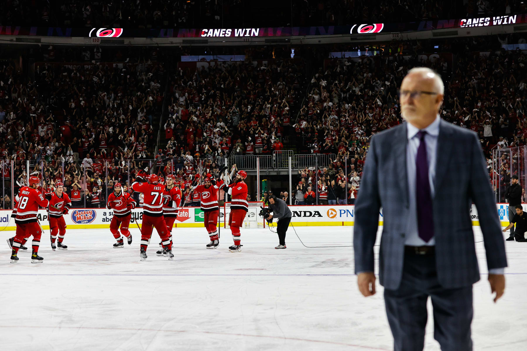 RALEIGH, NC - MAY 11: Carolina Hurricanes celebrate with their teammates while New Jersey Devils head coach Lindy Ruff exits the ice during the overtime of Eastern Conference Game Five of the Second Round of the 2023 Stanley Cup Playoffs at PNC Arena on May 11, 2023 in Raleigh, North Carolina. Hurricanes defeat Devils 3-2. (Photo by Jaylynn Nash/Getty Images)
