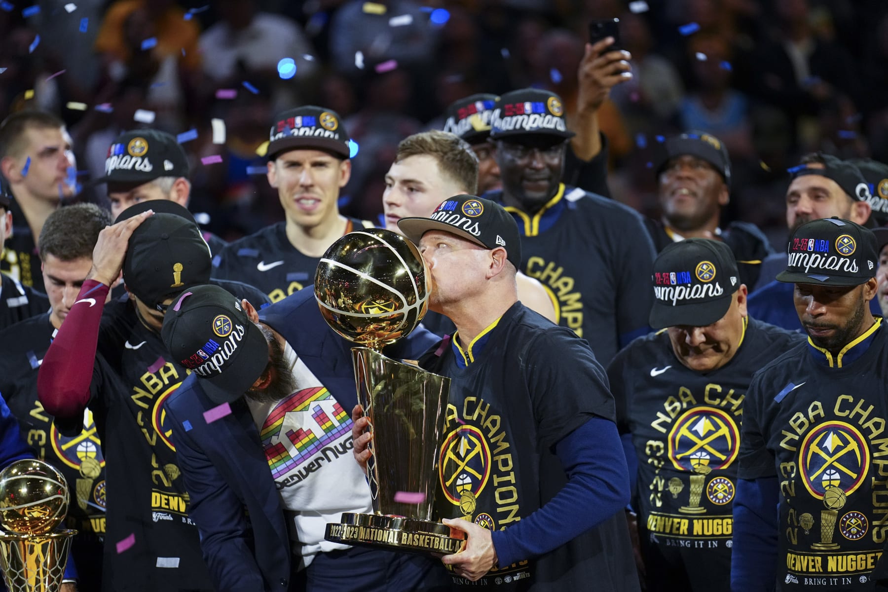 Denver Nuggets head coach Michael Malone, center, kisses the Larry O'Brien NBA Championship Trophy after the team's victory over the Miami Heat in Game 5 of basketball's NBA Finals, Monday, June 12, 2023, in Denver. (AP Photo/David Zalubowski)