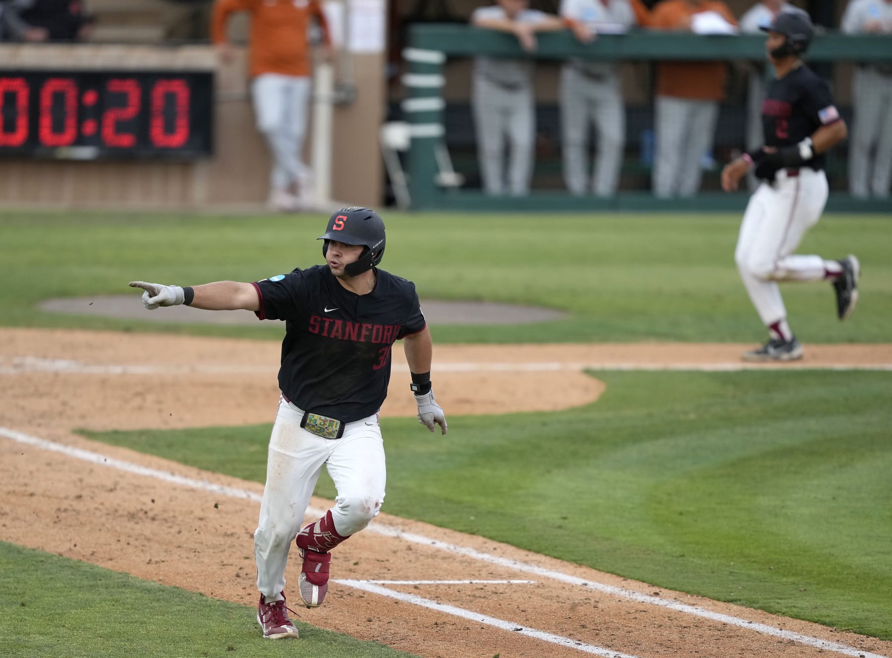 Stanford's Carter Graham, left, points to the dugout after hitting a single to drive in a run against Texas in the fourth inning of an NCAA college baseball tournament super regional game in Stanford, Calif., Monday, June 12, 2023. (AP Photo/Tony Avelar)