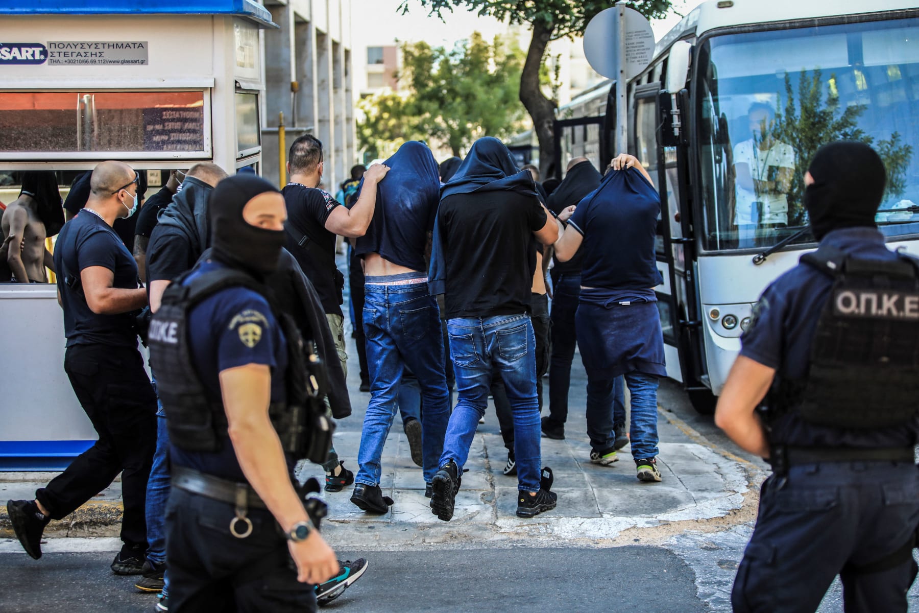 Soccer fans, most of them from Croatia, cover their faces while leaving the Athens Police Headquarters in Athens, as they are being detained as part of the inquiry on the death of a Greek fan during violent clashes on August 9, 2023. More than a hundred people, including 94 Croats, are to appear before the Athens prosecutor's office, suspected of being involved in the death of a Greek fan during violent clashes on August 7 evening between supporters of the Croatian football club Dinamo Zagreb and the 'Aek of Athens in the suburbs of the Greek capital. (Photo by YIANNIS PANAGOPOULOS / EUROKINISSI / AFP) (Photo by YIANNIS PANAGOPOULOS/EUROKINISSI/AFP via Getty Images)