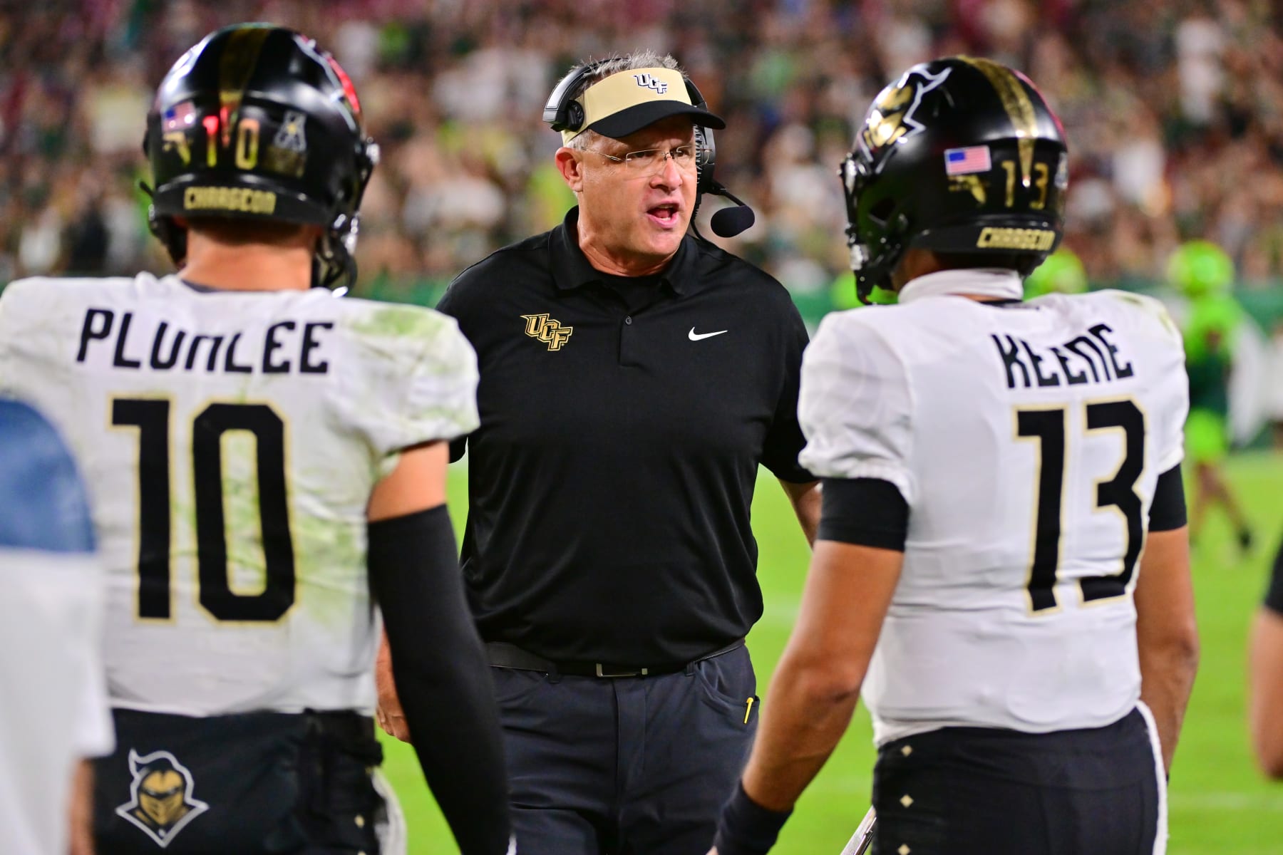 TAMPA, FLORIDA - NOVEMBER 26: Head coach Gus Malzahn of the UCF Knights talks with Mikey Keene #13 and John Rhys Plumlee #10 of the UCF Knights during the second half of a game against the South Florida Bulls at Raymond James Stadium on November 26, 2022 in Tampa, Florida. (Photo by Julio Aguilar/Getty Images)