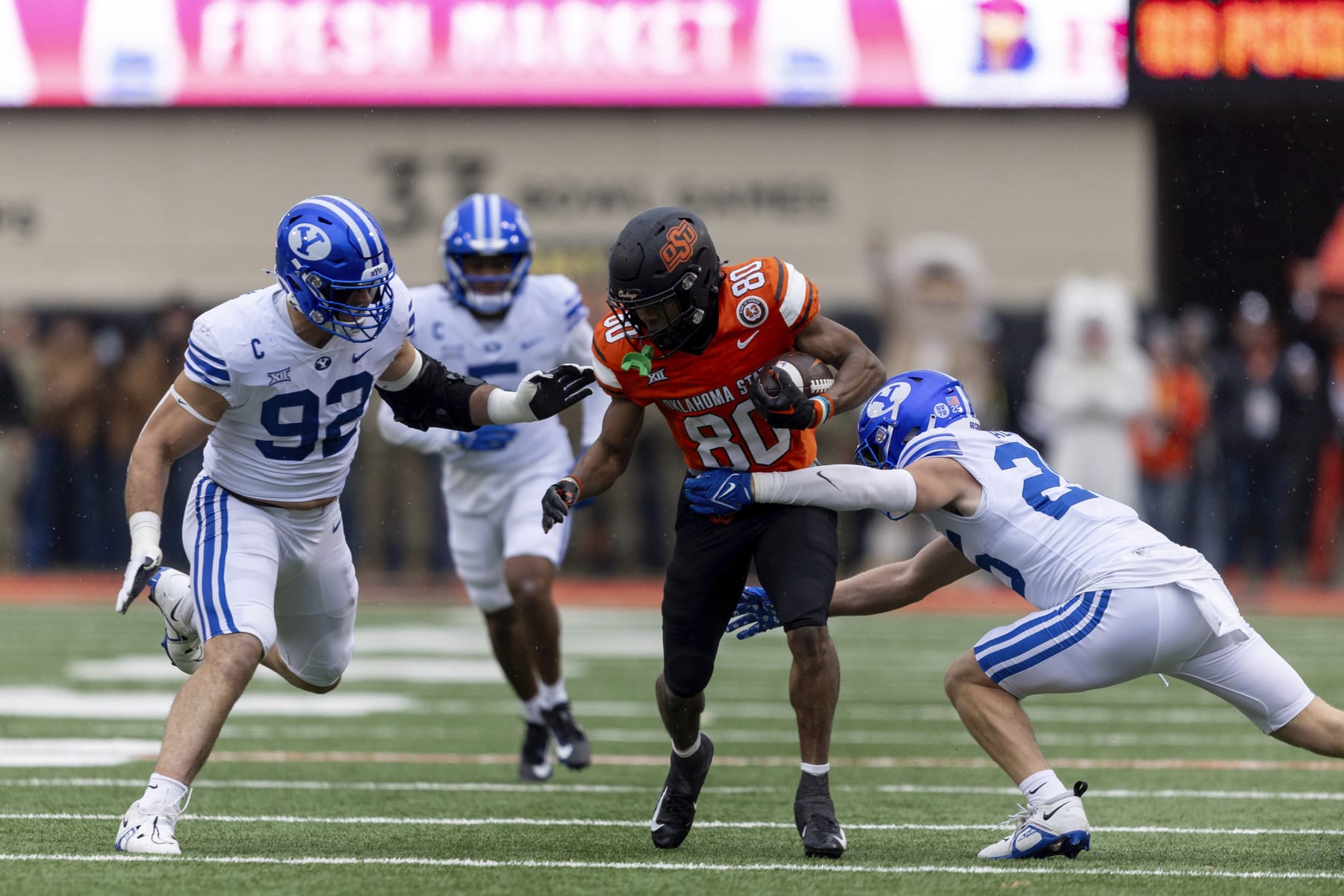BYU safety Talan Alfrey (25) and defensive end Tyler Batty (92) tackle Oklahoma State wide receiver Brennan Presley (80) in the first half of an NCAA college football game Saturday, Nov. 25, 2023, in Stillwater, Okla. (AP Photo/Mitch Alcala)