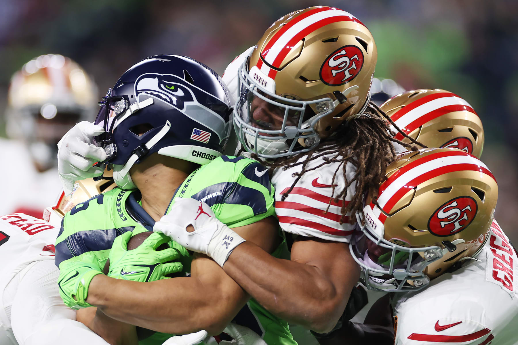 SEATTLE, WASHINGTON - NOVEMBER 23: Zach Charbonnet #26 of the Seattle Seahawks gets tackled by a slew of San Francisco 49ers defenders during the second quarter at Lumen Field on November 23, 2023 in Seattle, Washington. (Photo by Steph Chambers/Getty Images)