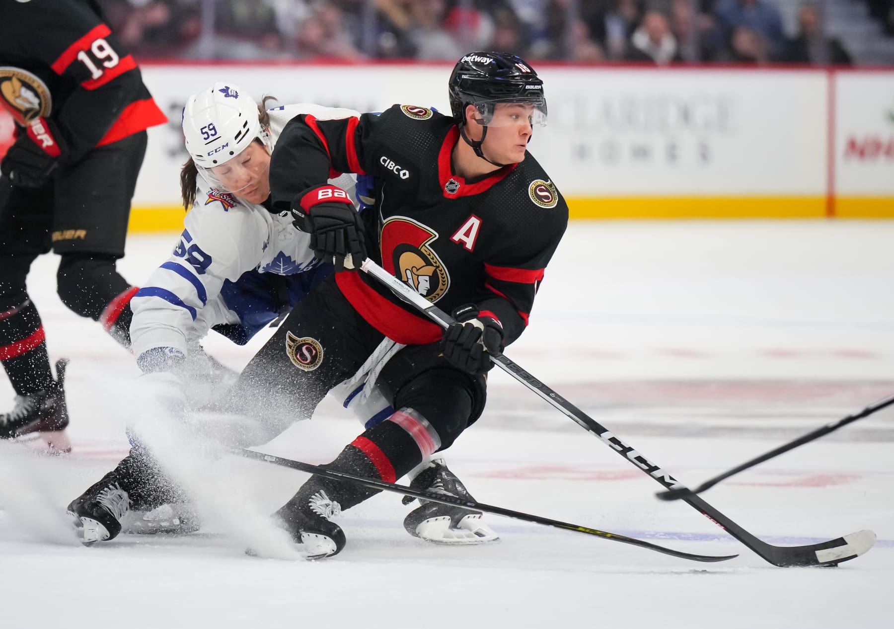 OTTAWA, CANADA - DECEMBER 7: Tim Stützle #18 of the Ottawa Senators controls the puck against Tyler Bertuzzi #59 of the Toronto Maple Leafs during the first period at Canadian Tire Centre on December 7, 2023 in Ottawa, Ontario, Canada. (Photo by André Ringuette/NHLI via Getty Images)