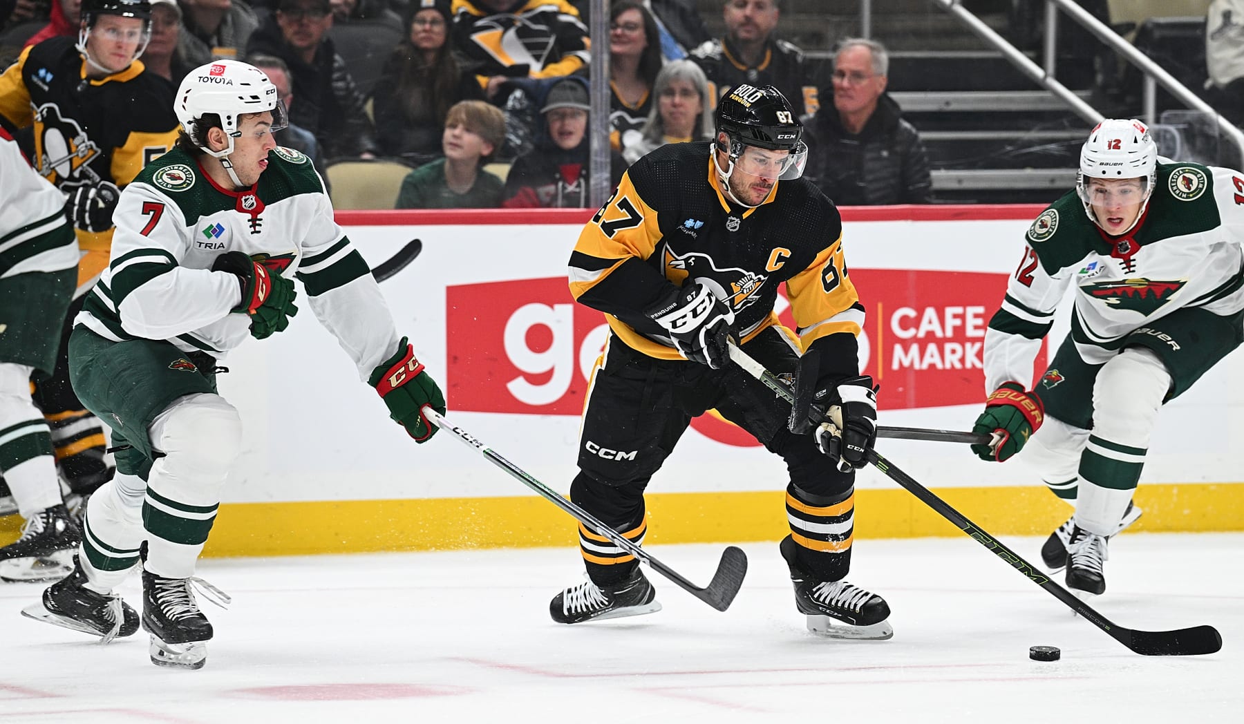 PITTSBURGH, PENNSYLVANIA - DECEMBER 18: Sidney Crosby #87 of the Pittsburgh Penguins skates with the puck against Brock Faber #7 of the Minnesota Wild in the first period during the game at PPG PAINTS Arena on December 18, 2023 in Pittsburgh, Pennsylvania. (Photo by Justin Berl/Getty Images)