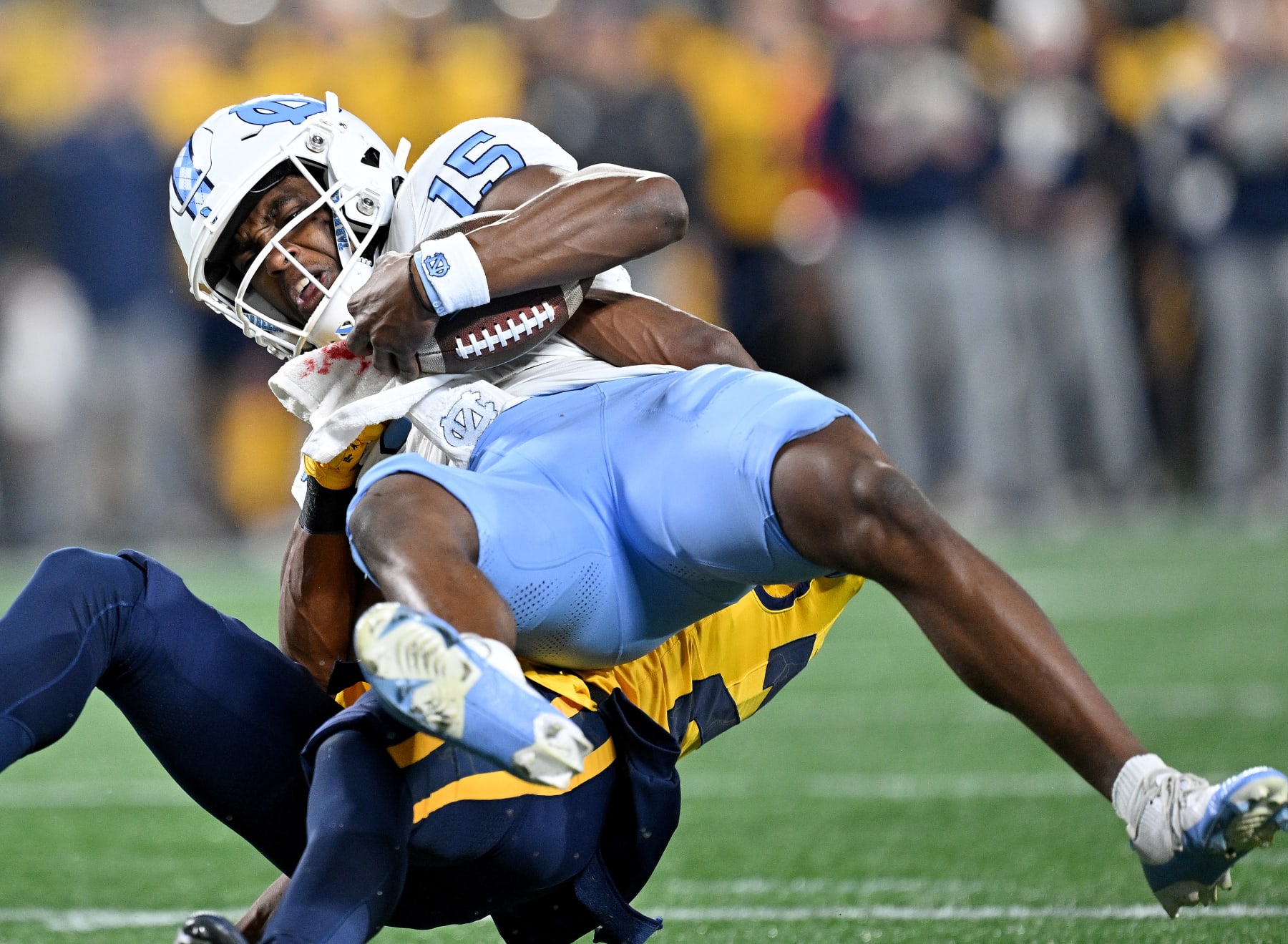 CHARLOTTE, NORTH CAROLINA - DECEMBER 27: Marcis Floyd #24 of the West Virginia Mountaineers tackles Conner Harrell #15 of the North Carolina Tar Heels during the first half of the Duke's Mayo Bowl at Bank of America Stadium on December 27, 2023 in Charlotte, North Carolina. (Photo by Grant Halverson/Getty Images)
