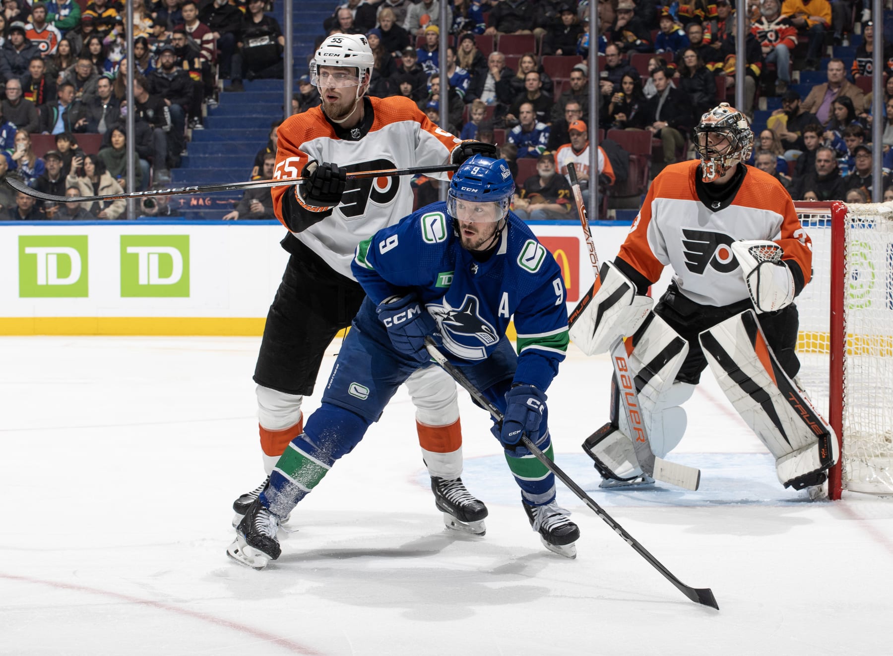 VANCOUVER, CANADA - DECEMBER 28: J.T. Miller #9 of the Vancouver Canucks and Rasmus Ristolainen #55 of the Philadelphia Flyers battle for the puck during the second period of their NHL game at Rogers Arena on December 28, 2023 in Vancouver, British Columbia, Canada. (Photo by Jeff Vinnick/NHLI via Getty Images)