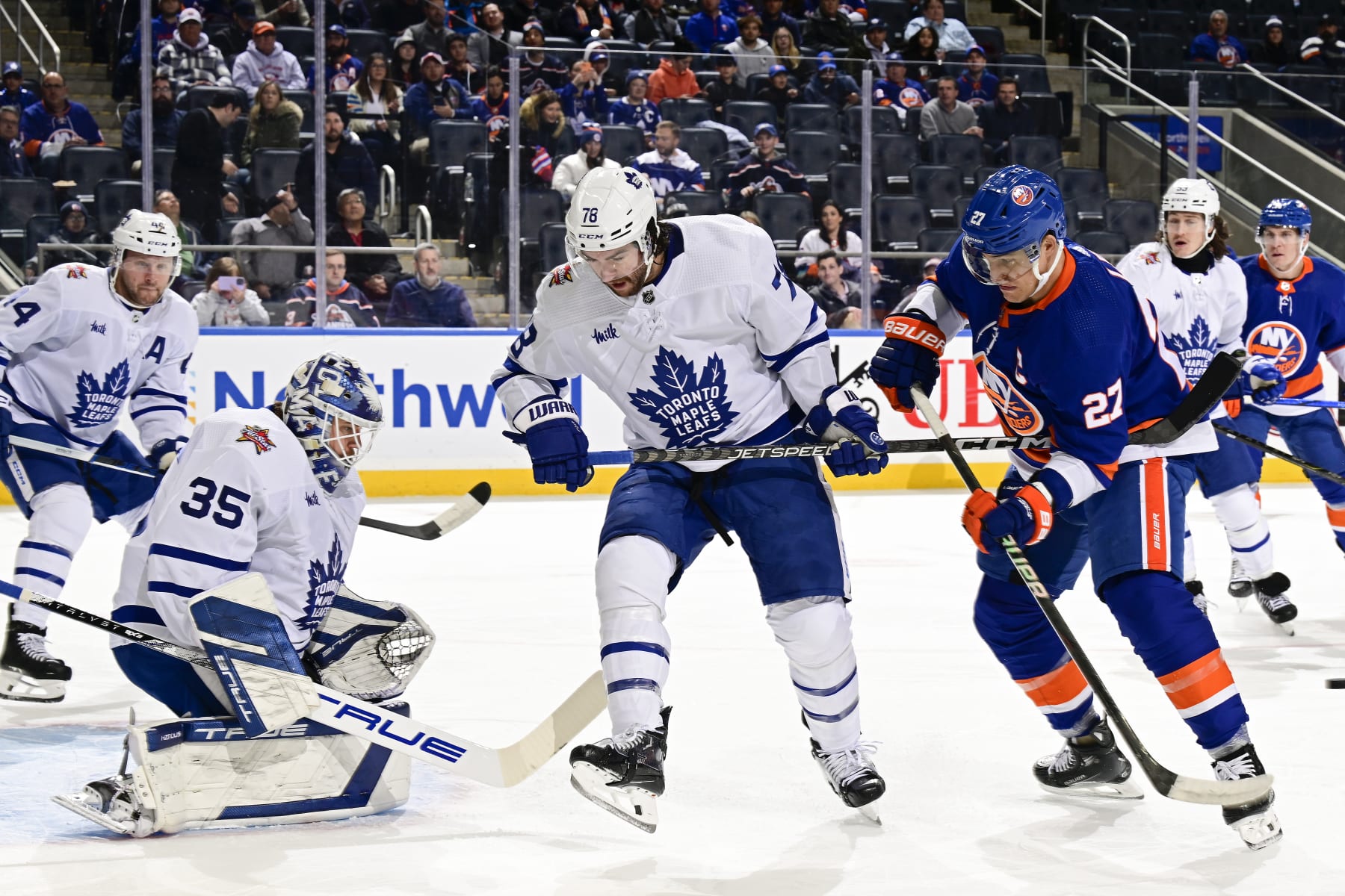 ELMONT, NEW YORK - DECEMBER 11: TJ Brodie #78 of the Toronto Maple Leafs defends Anders Lee #27 of the New York Islanders as Ilya Samsonov #35 tends net during the first period at UBS Arena on December 11, 2023 in Elmont, New York. (Photo by Steven Ryan/NHLI via Getty Images)