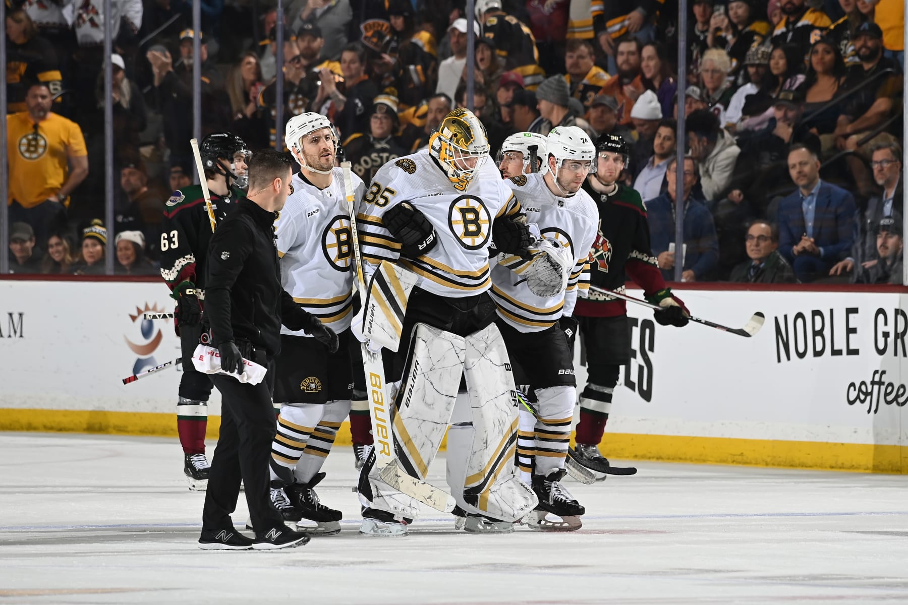 TEMPE, ARIZONA - JANUARY 09: Linus Ullmark #35 of the Boston Bruins is helped off the ice by teammates Kevin Shattenkirk #12 and Jake DeBrusk #74 during overtime against the Arizona Coyotes at Mullett Arena on January 09, 2024 in Tempe, Arizona. (Photo by Norm Hall/NHLI via Getty Images)