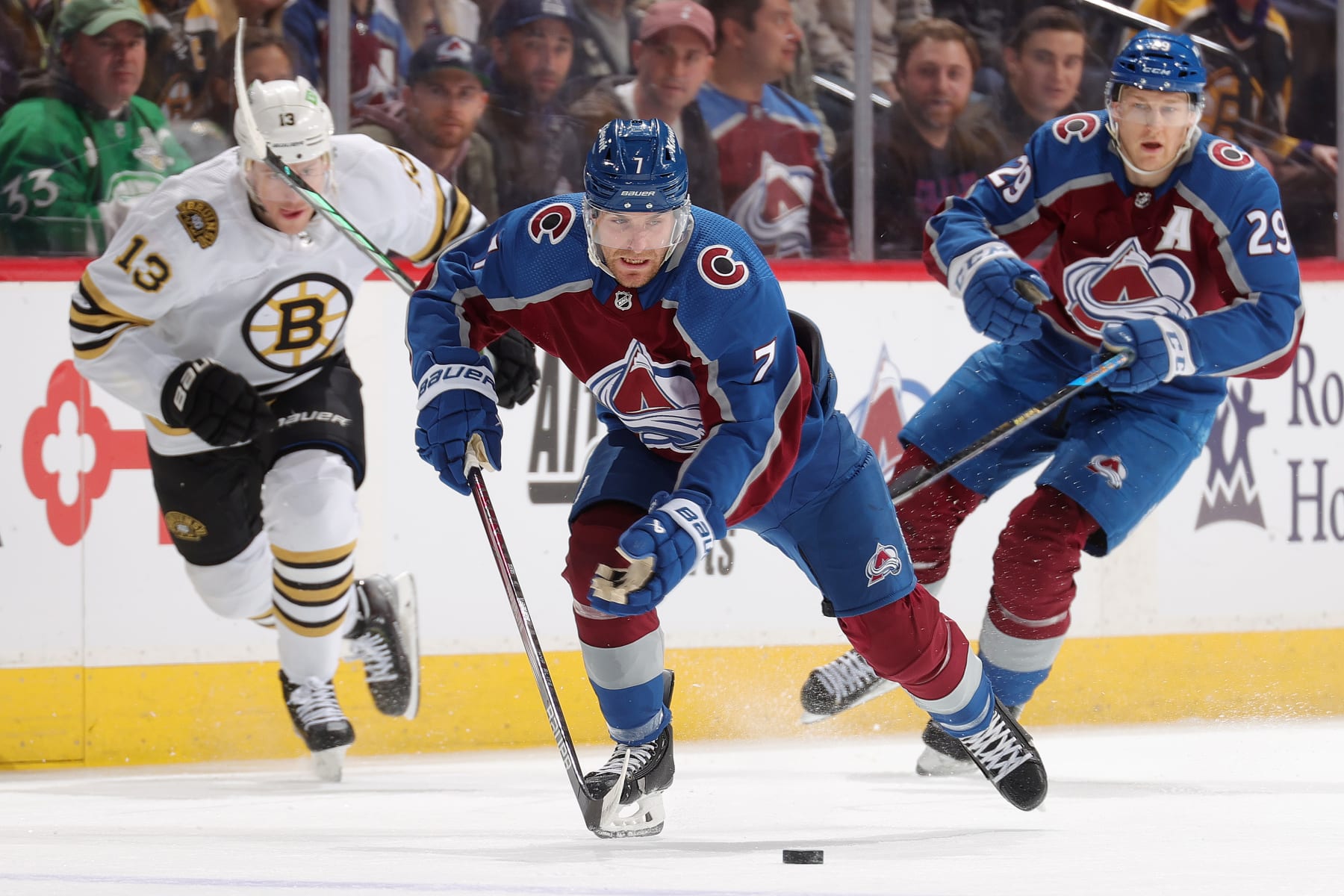 DENVER, COLORADO - JANUARY 08: Devon Toews #7 and Nathan MacKinnon #29 of the Colorado Avalanche skate against Charlie Coyle #13 of the Boston Bruins at Ball Arena on January 8, 2024 in Denver, Colorado. (Photo by Michael Martin/NHLI via Getty Images)